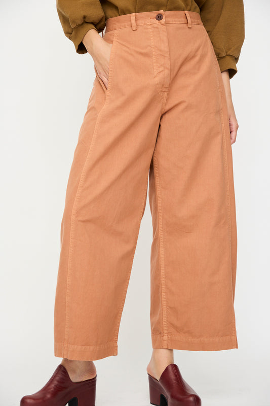 A person wearing the Rachel Comey Garra Pant in Copper with burgundy heeled shoes stands with one hand in a pocket.