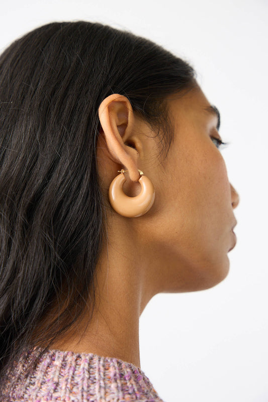 Close-up side view of a person with long dark hair wearing the Rachel Comey Grass Earring in Mustard and a textured, mustard-colored sweater.