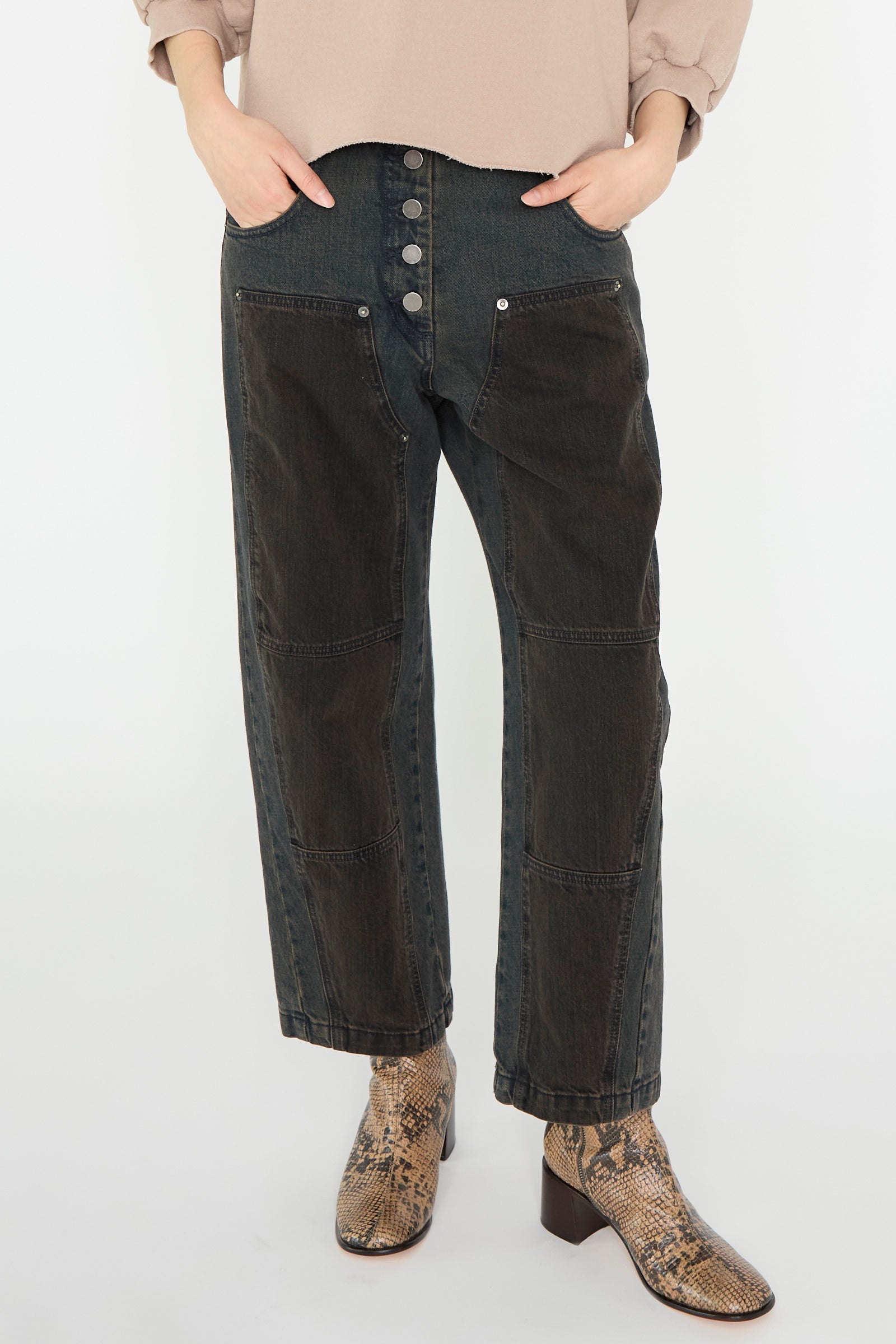 Person wearing Rachel Comey's Handy Pant in Brown, featuring relaxed fit high-waisted jeans with large buttons, hands in pockets, paired with brown snakeskin boots.