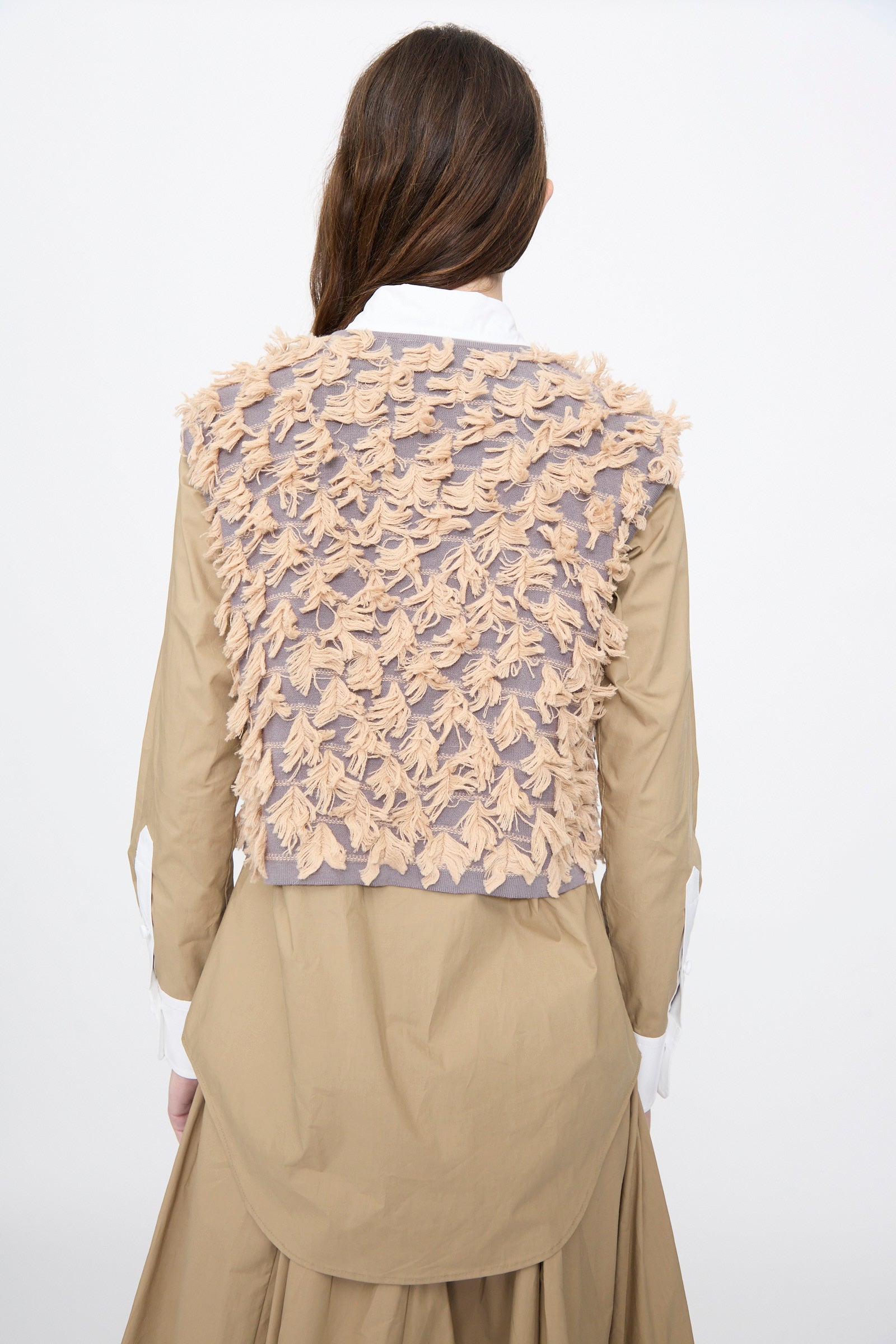 A person with long brown hair wears the Rachel Comey Hazlitt Top in Dusty Mauve-Blush, layered over a tan dress, facing away from the camera against a plain white background.