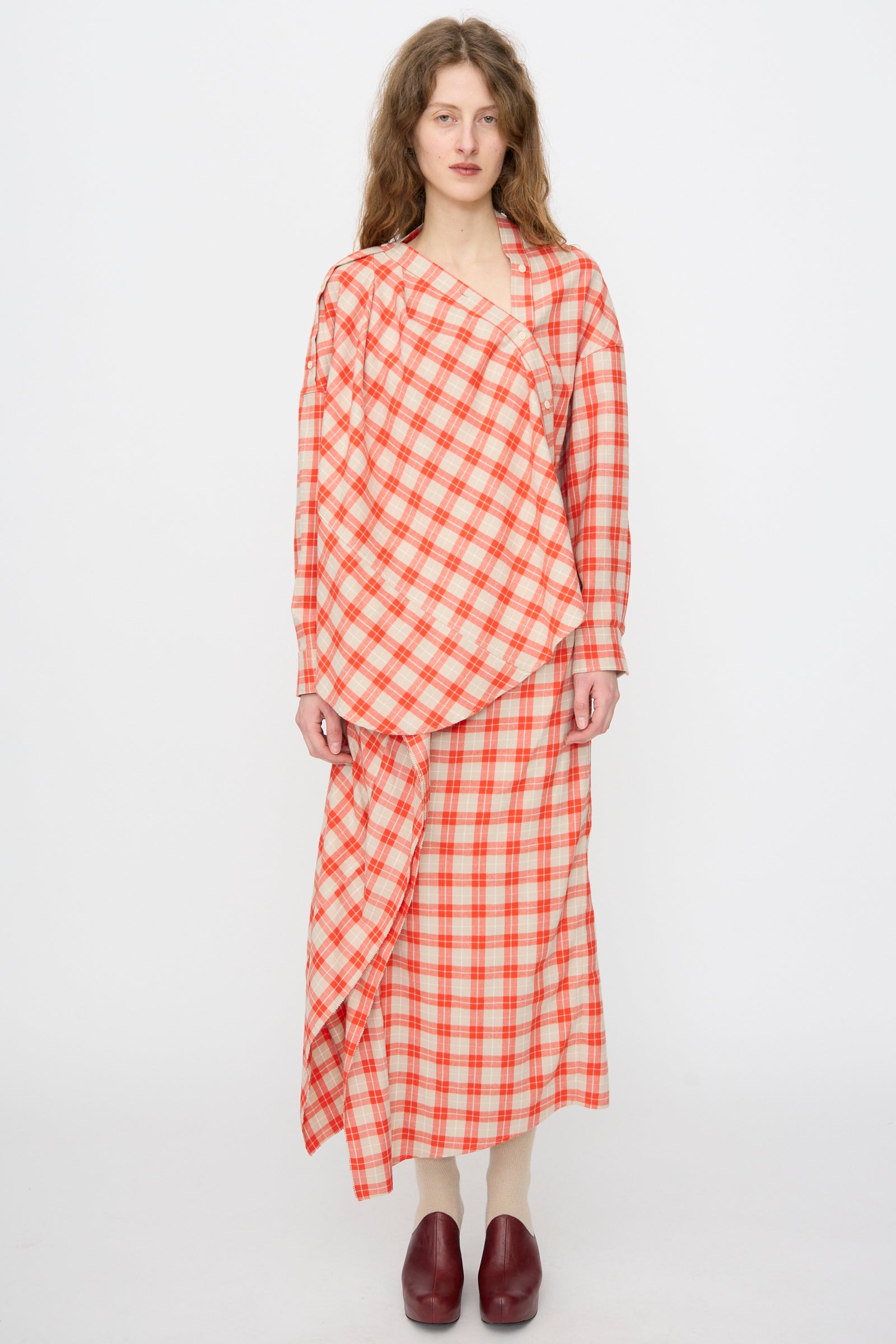 A person stands against a white background wearing the Hollow Top in Red by Rachel Comey, styled with a matching long skirt, cream tights, and burgundy shoes.