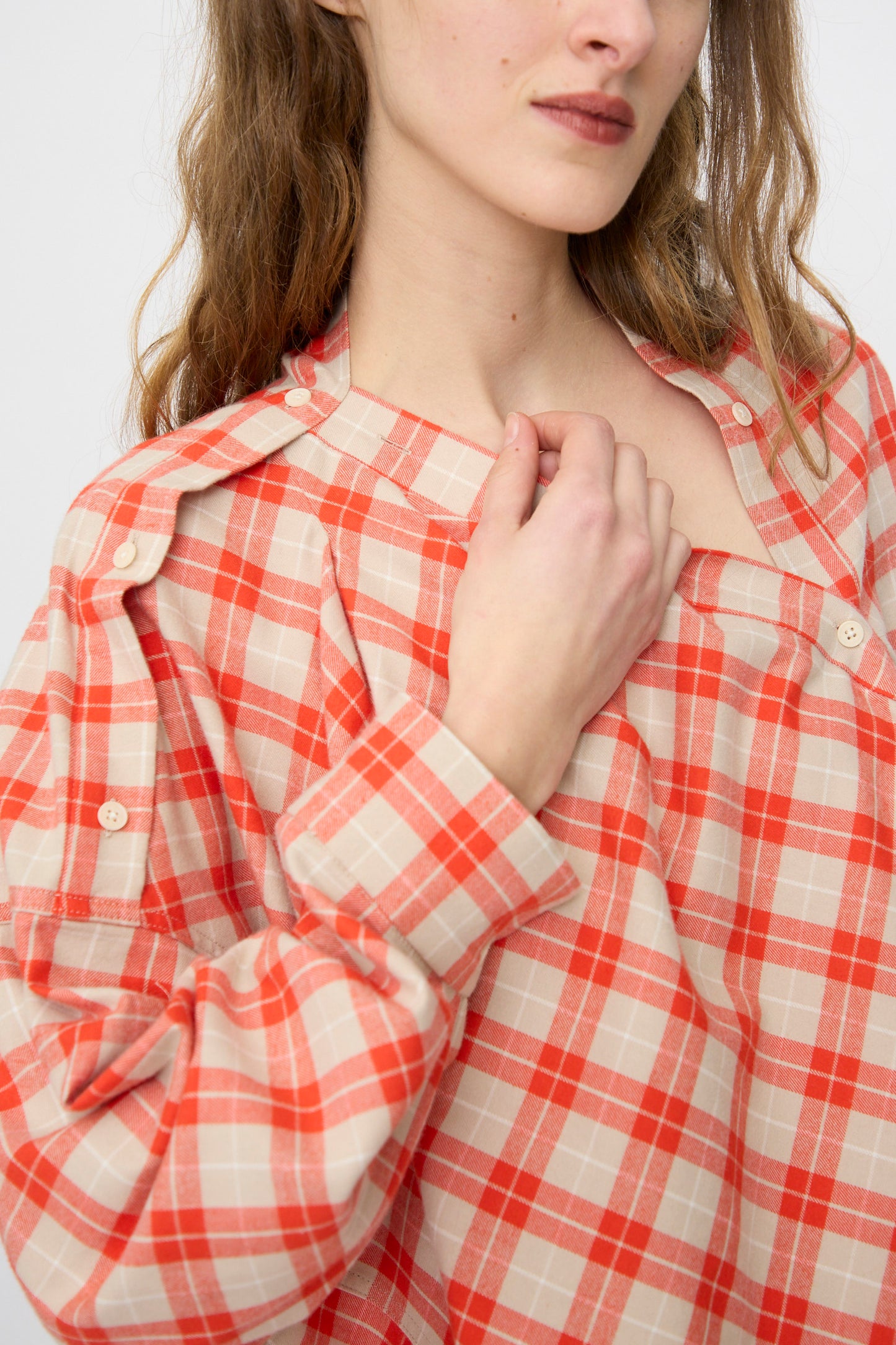 A person wearing the Rachel Comey Hollow Top in red holds the collar with one hand, shown from the shoulders up against a plain background.