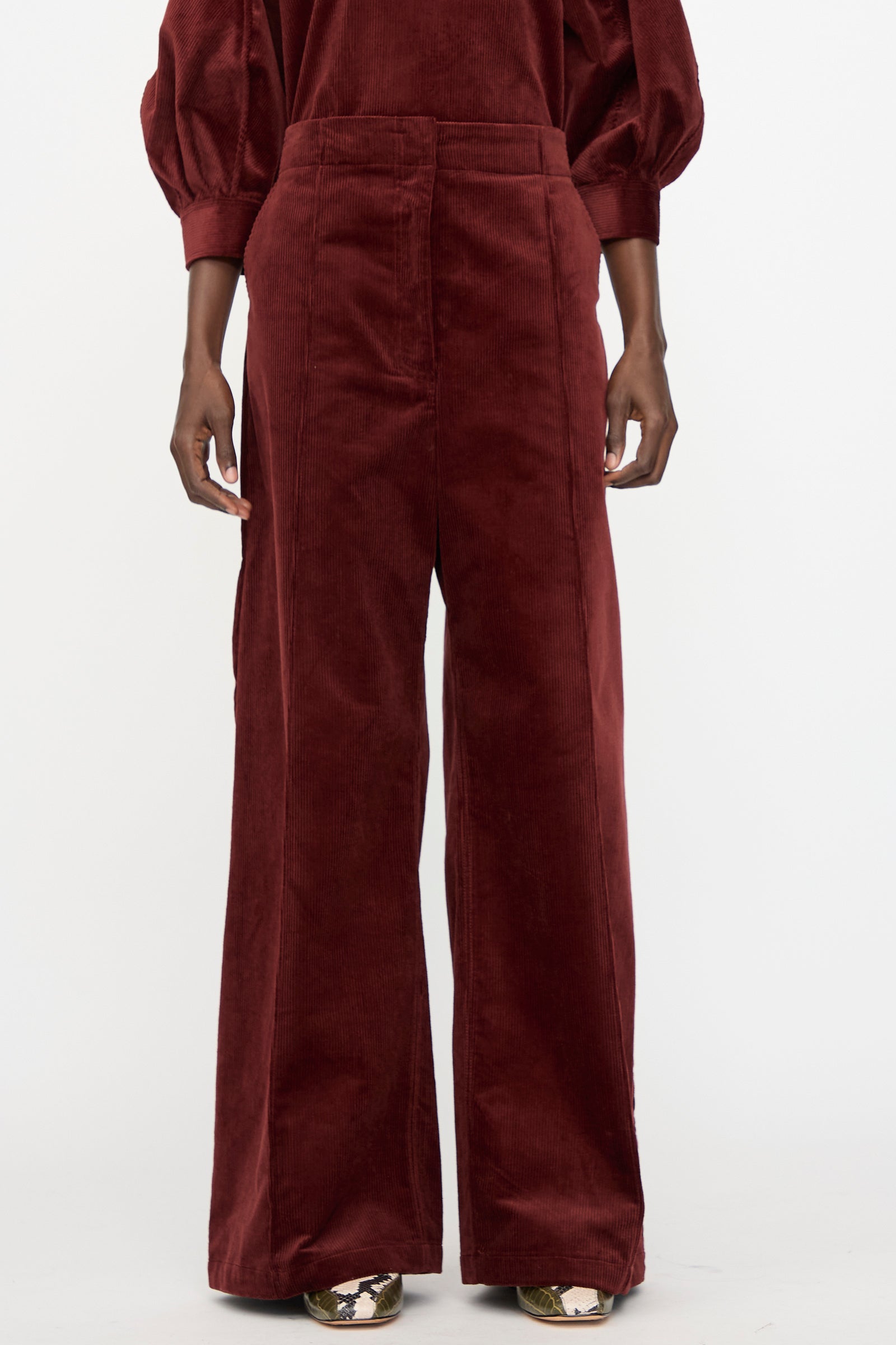 A person wears the Rachel Comey Lanett Cord Pant in Brick, a women's wide-leg stretch corduroy style, standing against a plain white background.