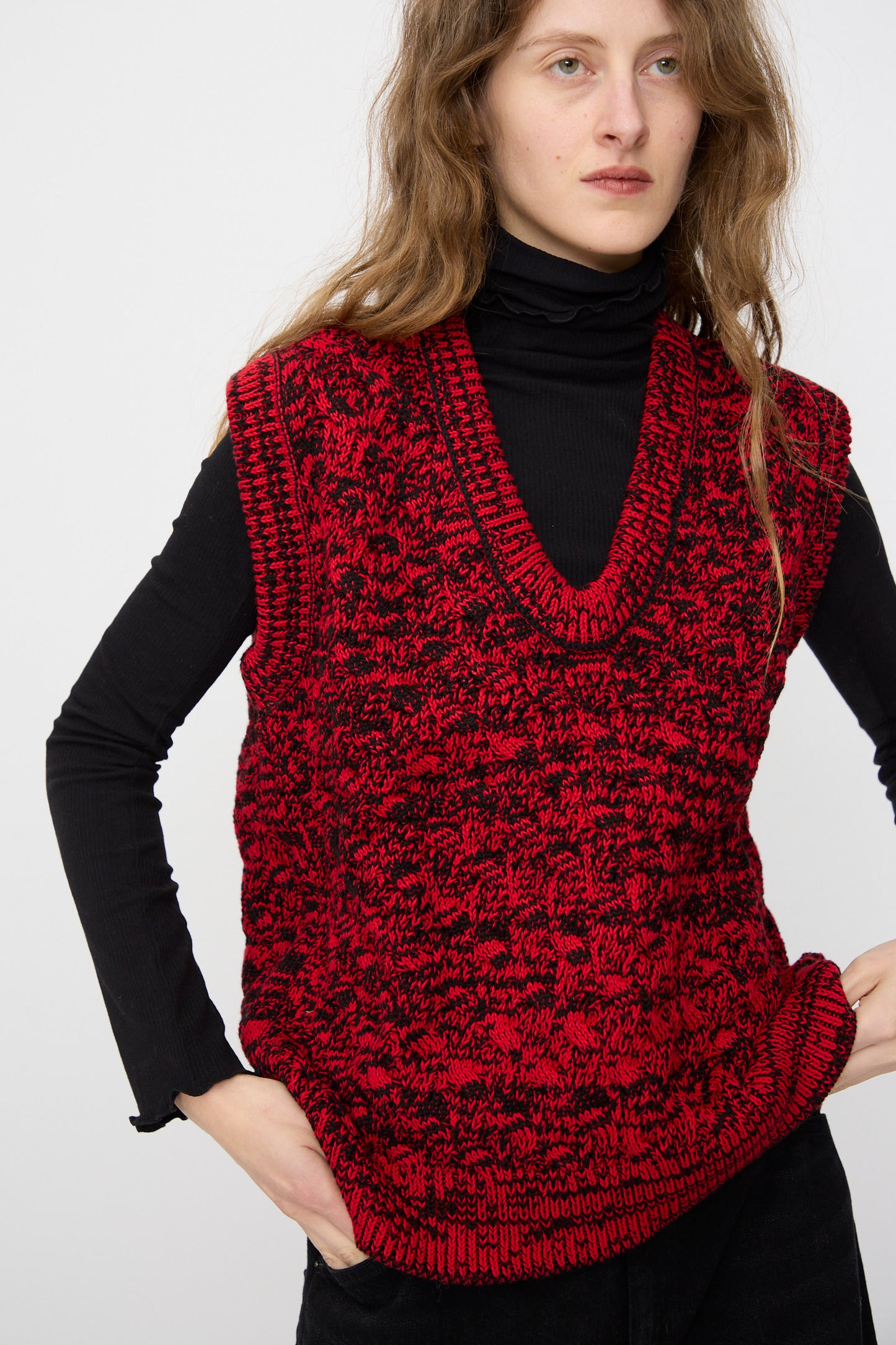 A person wearing the Rachel Comey Mati Vest in Red Marble, styled with a black turtleneck and relaxed fit, stands against a plain background.