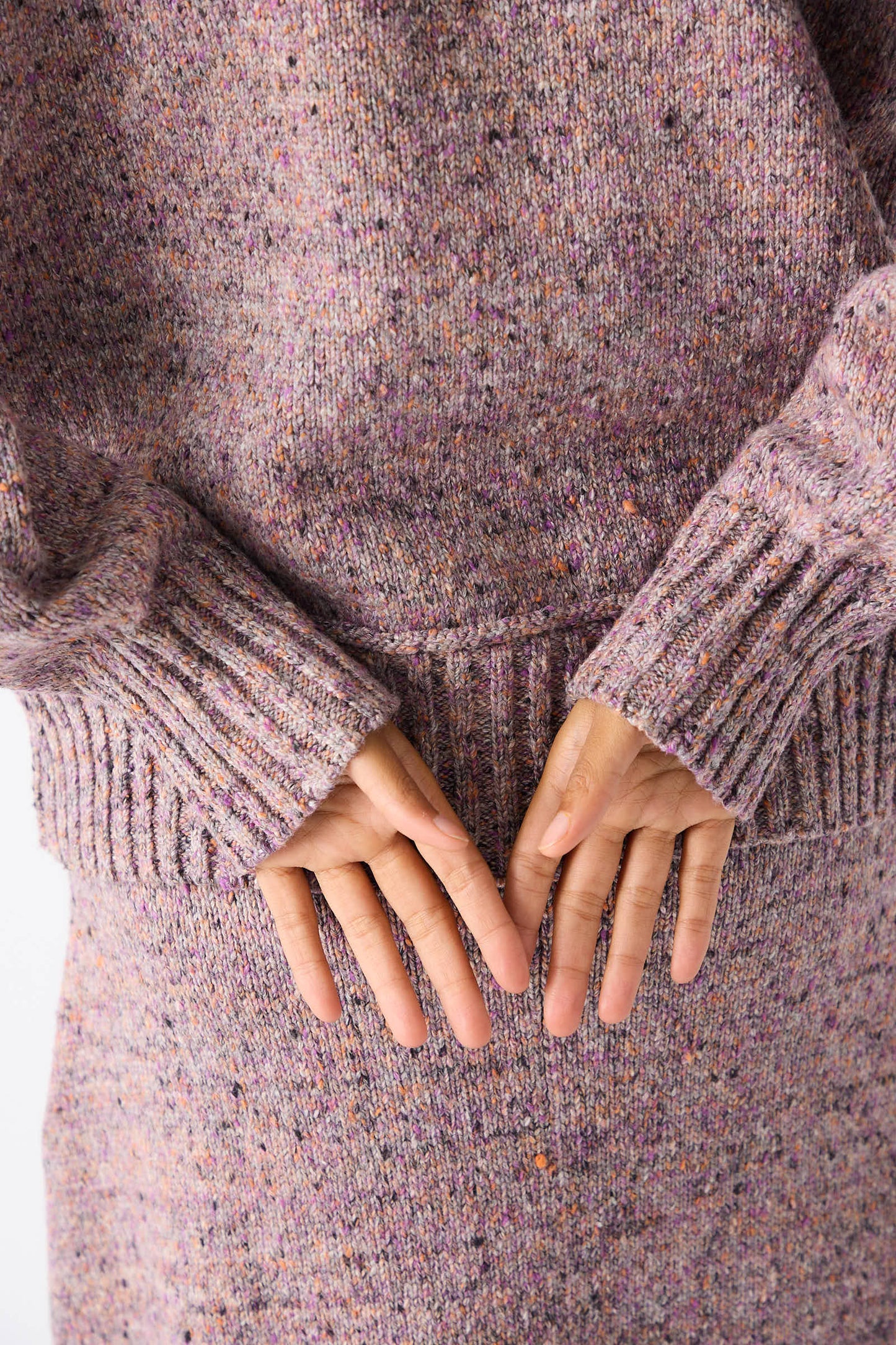 Close-up of a person wearing the Neps Tweed Knit Ninni Sweater in Violet by Rachel Comey, with hands clasped behind their back.