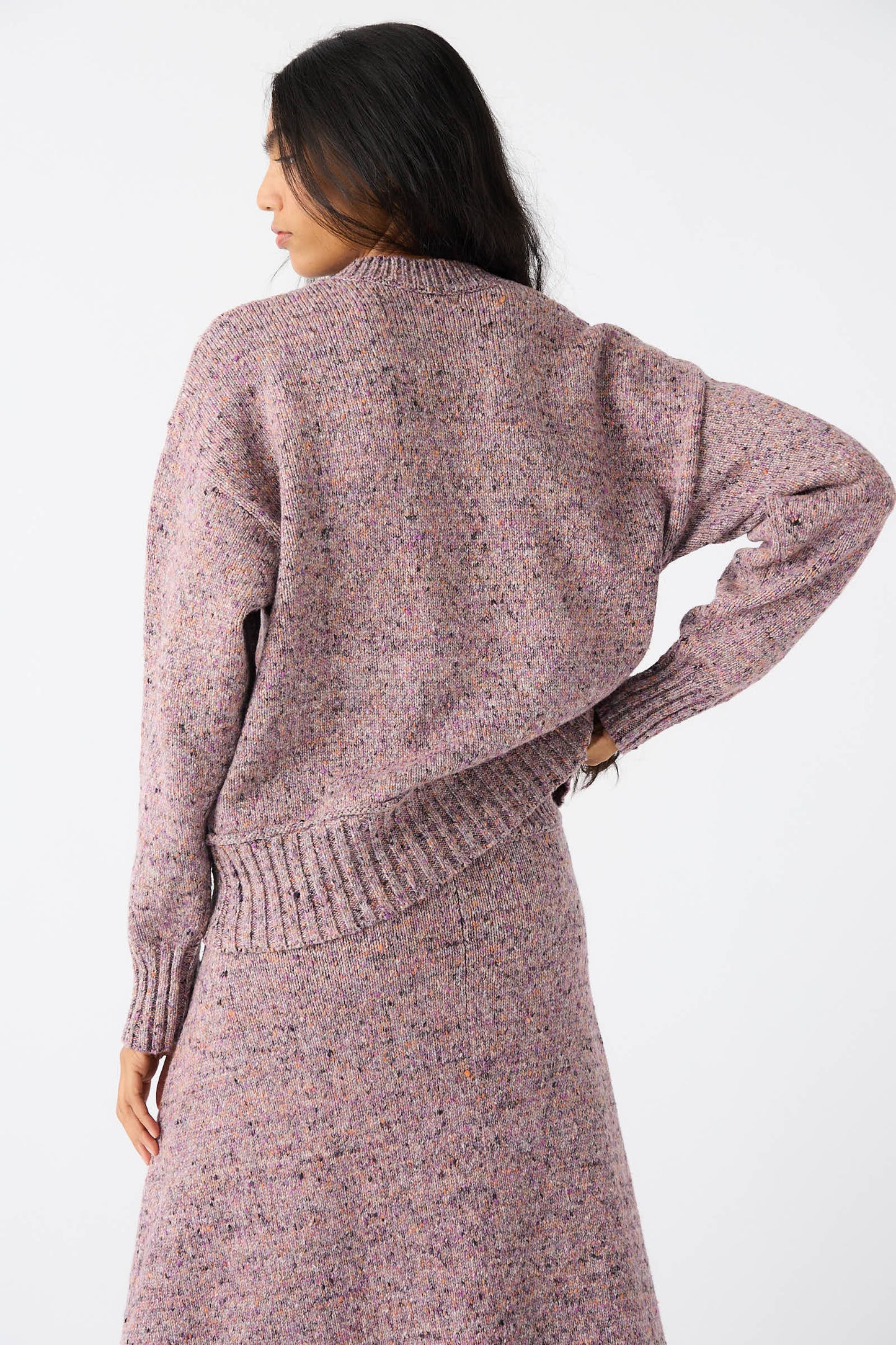 A person with long dark hair is shown from the back, wearing a Violet Neps Tweed Knit Ninni Sweater by Rachel Comey and a matching skirt.