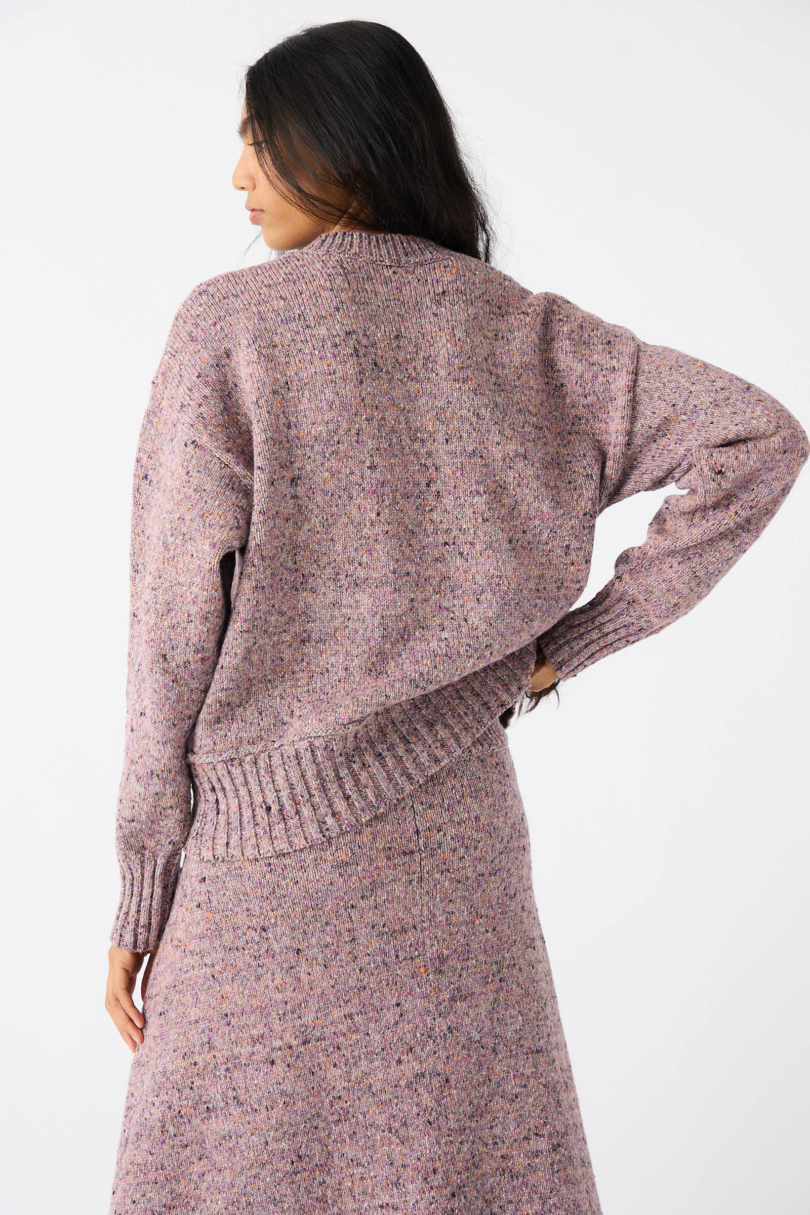 A person with long dark hair is shown from the back, wearing a Violet Neps Tweed Knit Ninni Sweater by Rachel Comey and a matching skirt.