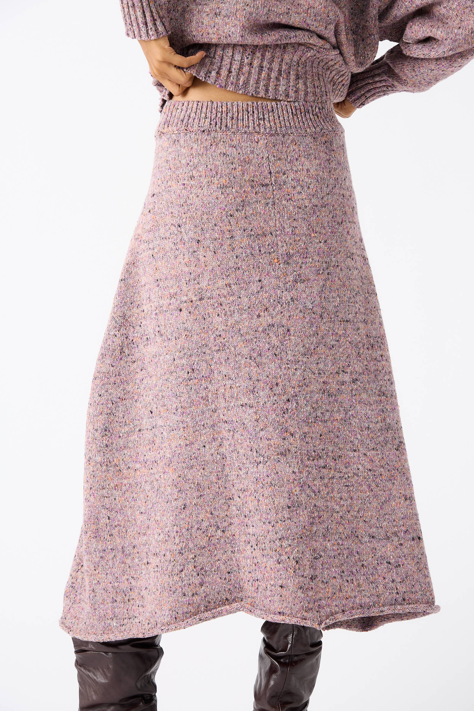 Person wearing a Rachel Comey Neps Tweed Knit Rapt Skirt in Violet, with one hand resting on their waist and dressed in brown knee-high boots.