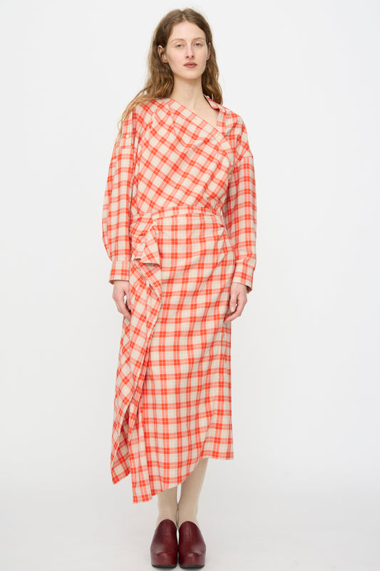 A woman stands against a plain background wearing the Rachel Comey Nesom Skirt in red, styled with an asymmetrical neckline top featuring ruffle details and paired with red shoes.