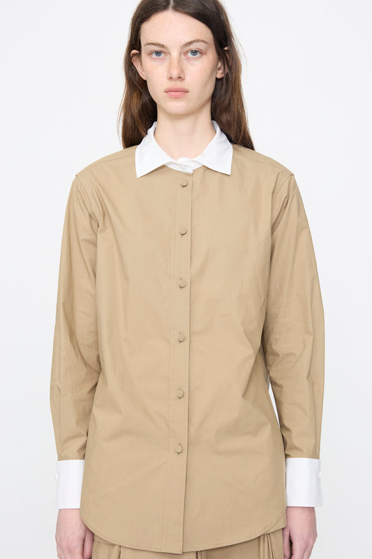 A woman stands facing forward against a plain white background, wearing the Rachel Comey Pierre Shirt in Khaki—an organic cotton shirt featuring a tailored fit with white collar and cuffs.