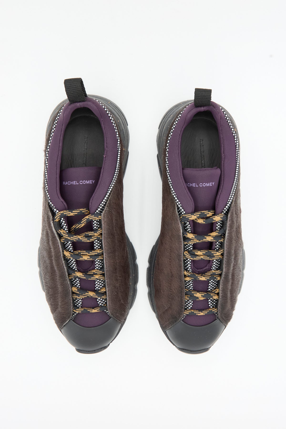 The Rachel Comey Pilla Sneaker in Chestnut, featuring brown textured calf hair uppers, black soles and toe caps, purple lining, and patterned laces, crafted in Portugal, is shown from above on a white background.