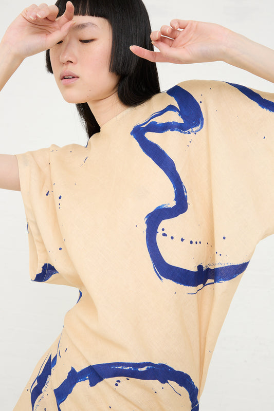 Woman in beige Rachel Comey Regent Dress in Blush with blue abstract printed design posing against a white background.