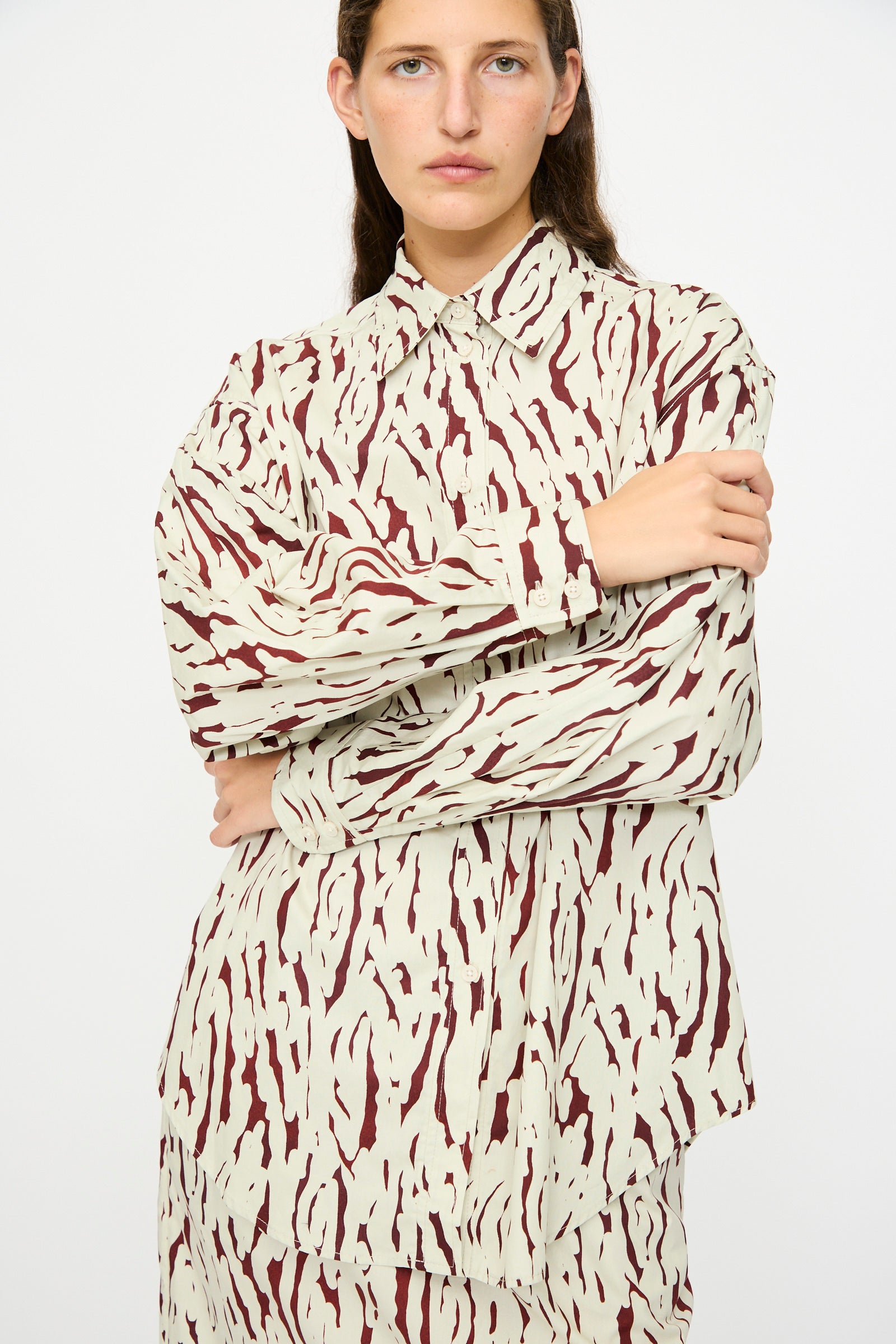 A person with long brown hair wears the Rachel Comey Risa Top in Cream and a maroon Tiikeri print skirt, standing against a plain white background.