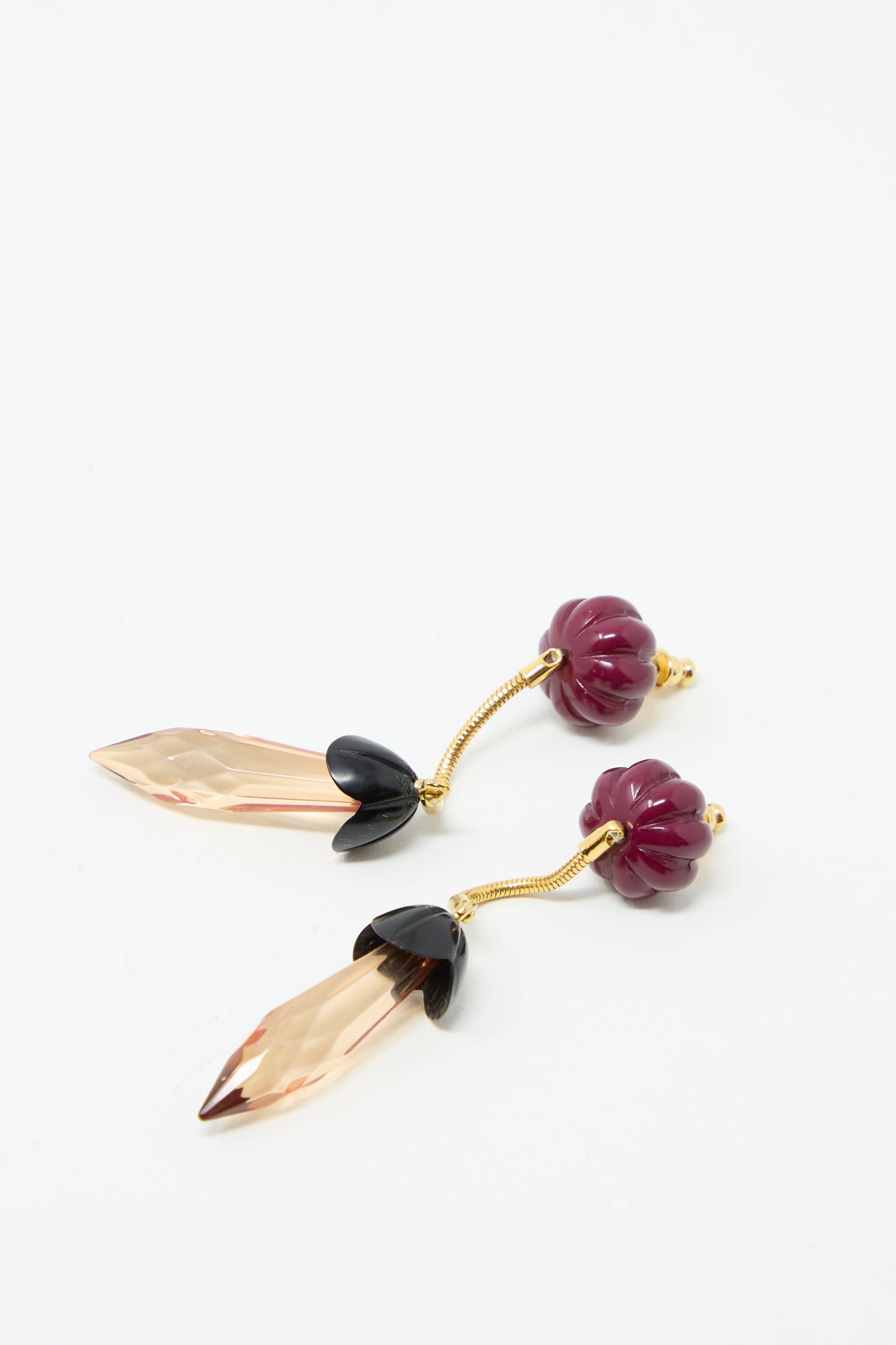 The Rosales Earring in Plum by Rachel Comey features a purple acrylic bead top with a gold stem, ending in a leaf-shaped gold and black bottom piece with metal drop detailing.