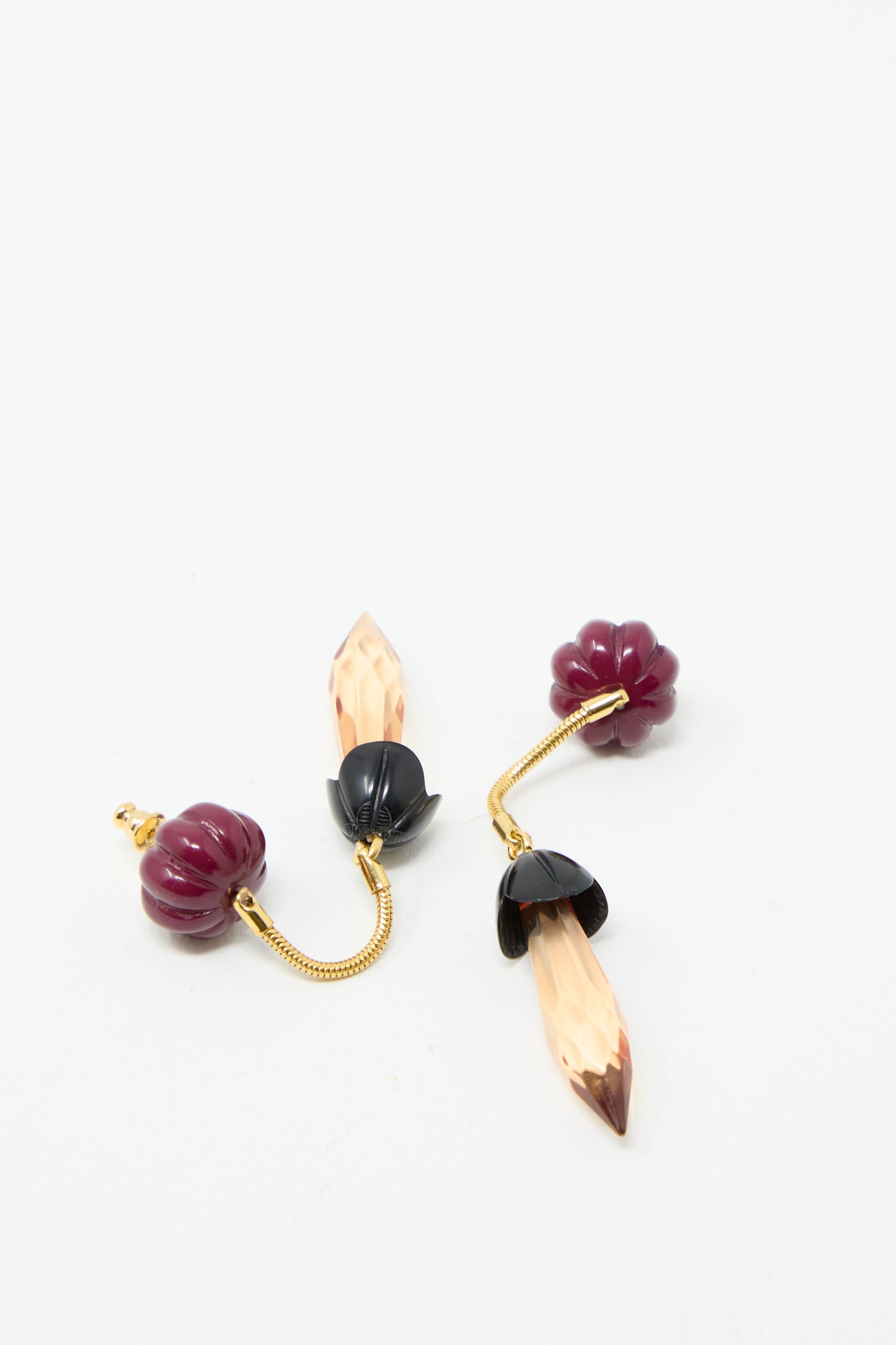 Two pairs of Rachel Comey's Rosales Earrings in Plum, featuring deep red, black, and gold with faceted pendants and metal drop detailing on a plain white background.