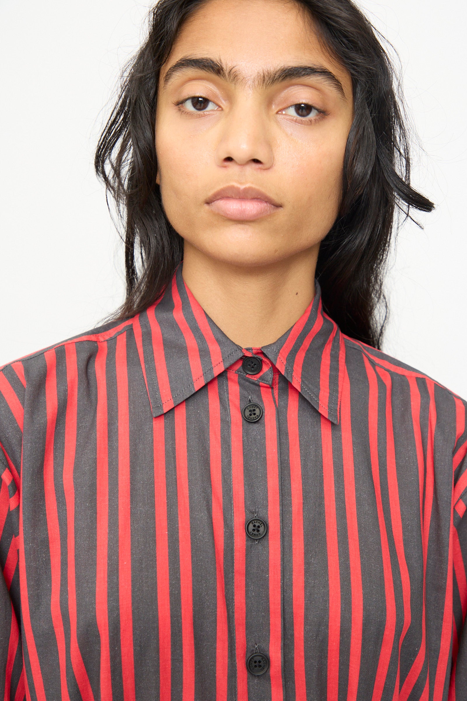 A person with long dark hair wears the Rachel Comey Smith Stripe Olli Jumpsuit in Red, featuring vertical stripes, while looking directly at the camera against a plain background.