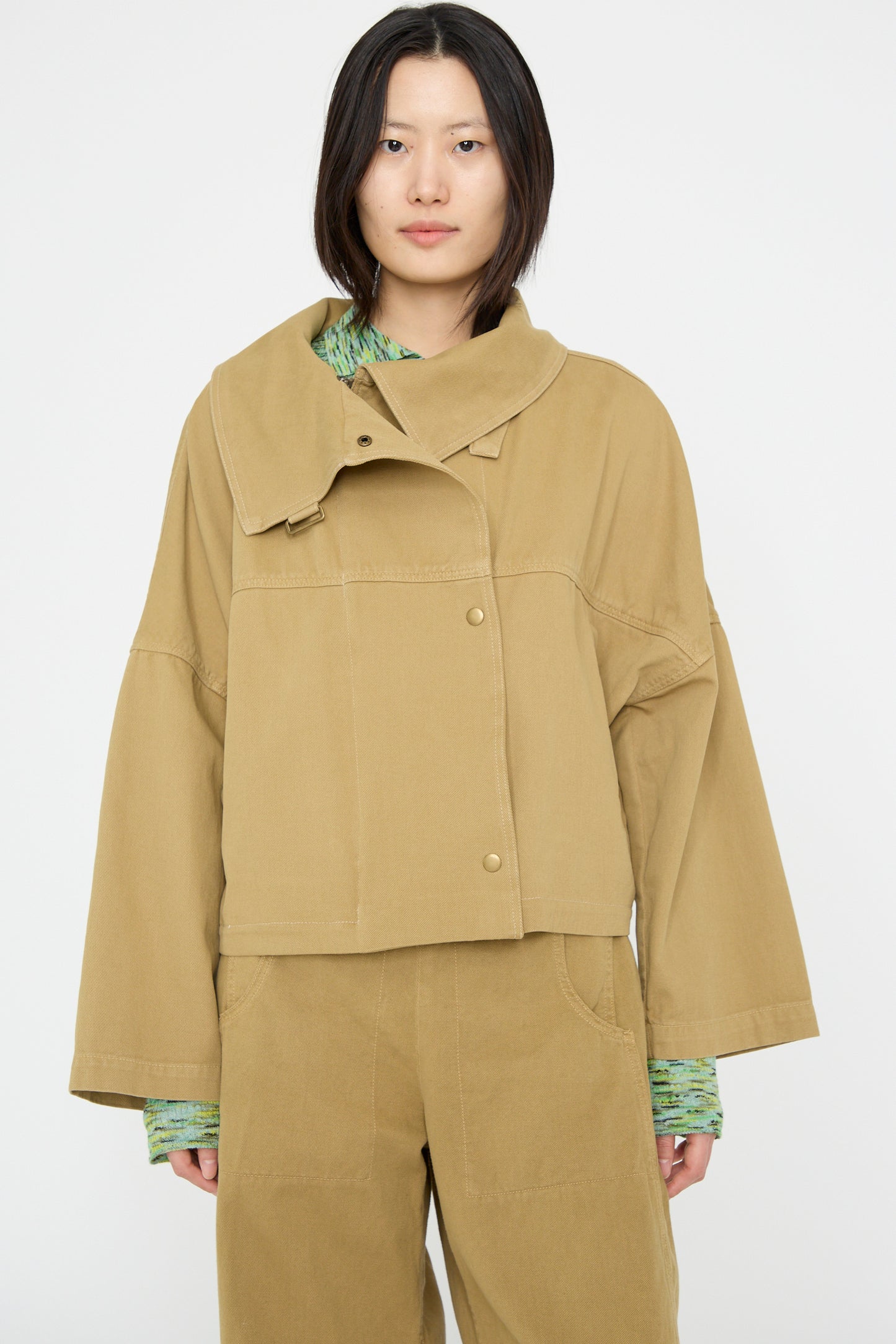 A person is wearing a Vansire Jacket in Olive by Rachel Comey, styled with matching pants and a green shirt, standing against a plain background.