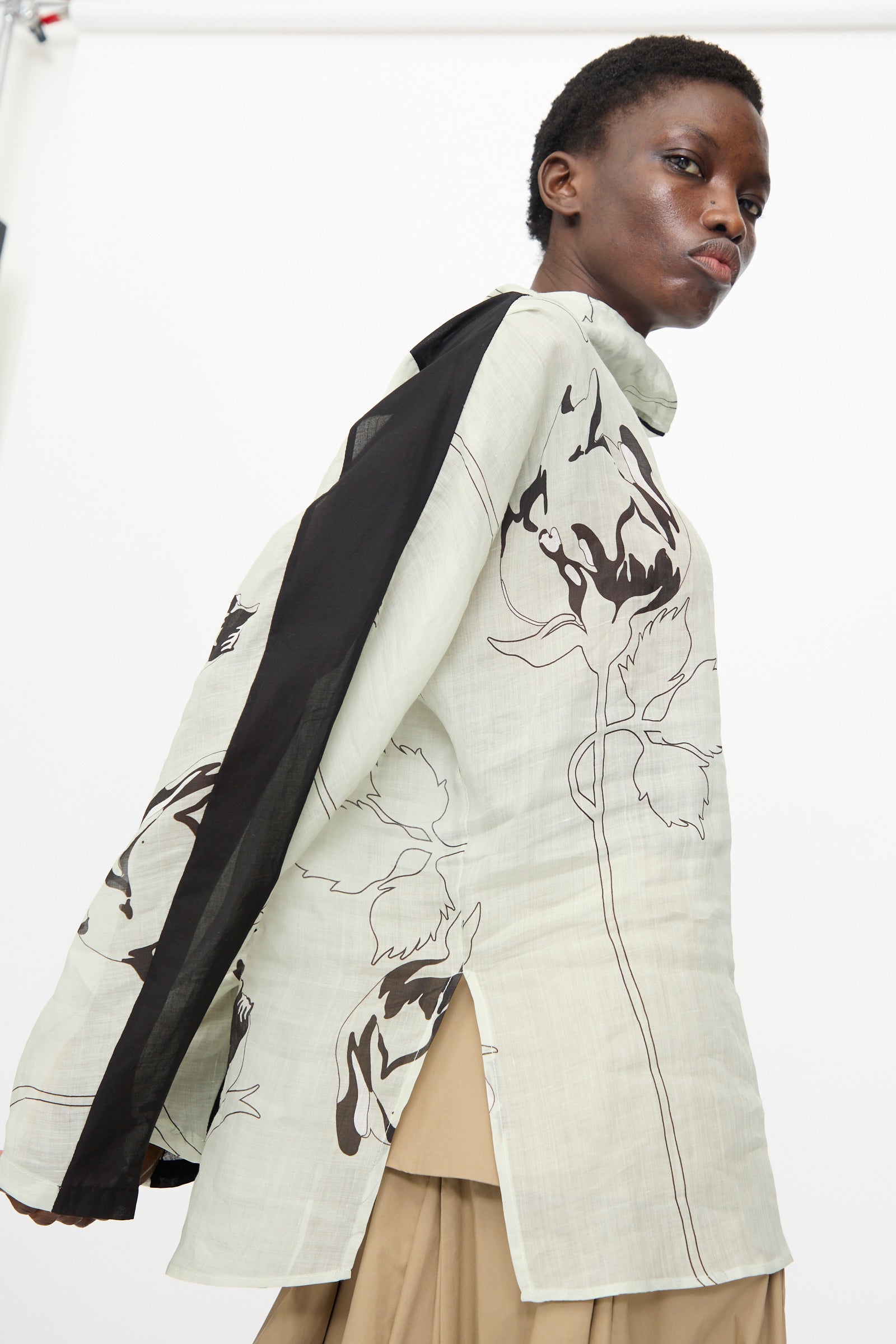 Model wears the Rachel Comey Wanson Top in Dove, a light-colored long sleeve shirt with floral print and black accents, paired with beige pants against a plain white background.