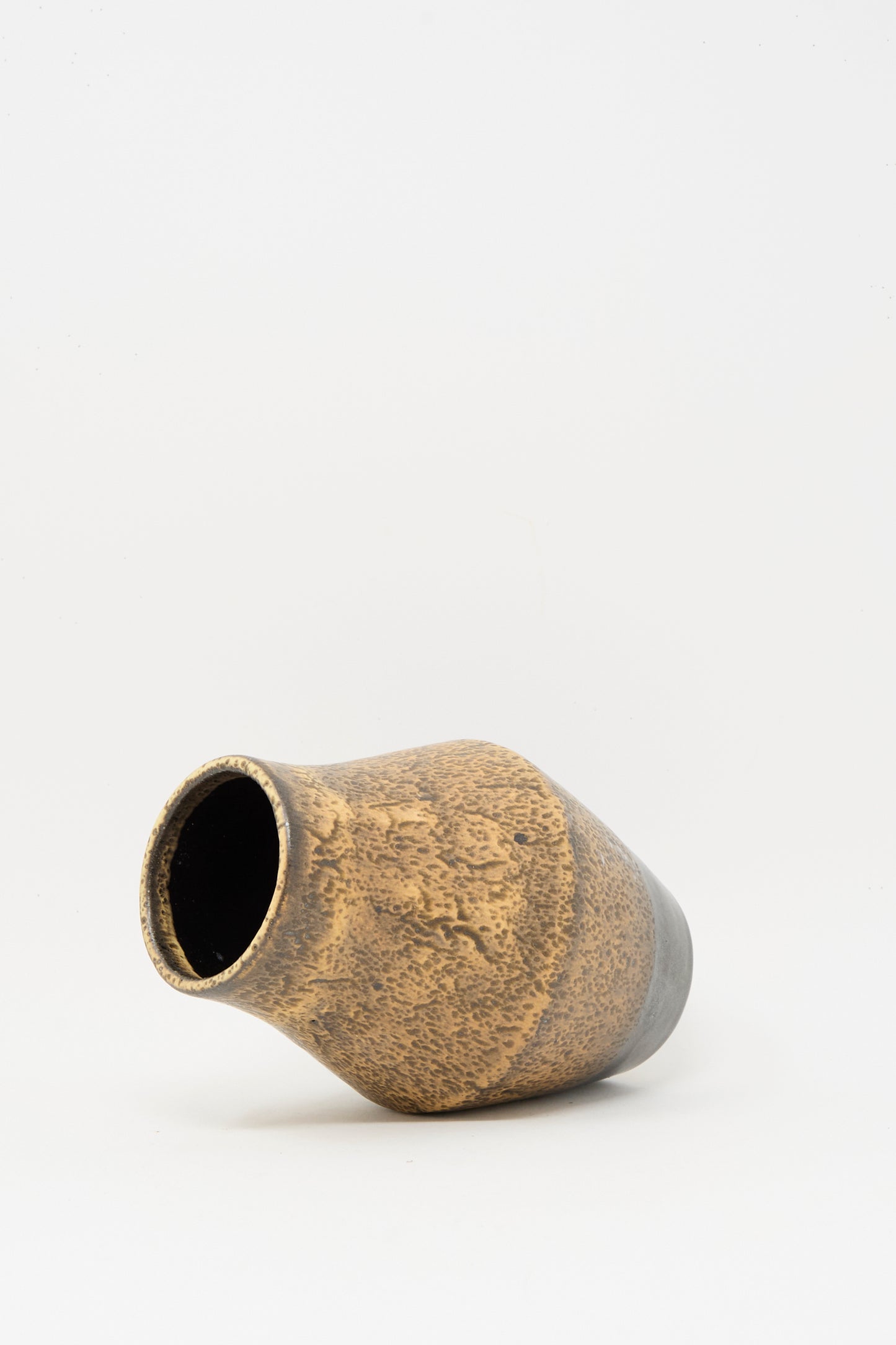The Small Sap Vase in Brown by Rachel Craven, featuring a textured clay surface, is shown lying on its side against a plain white background.
