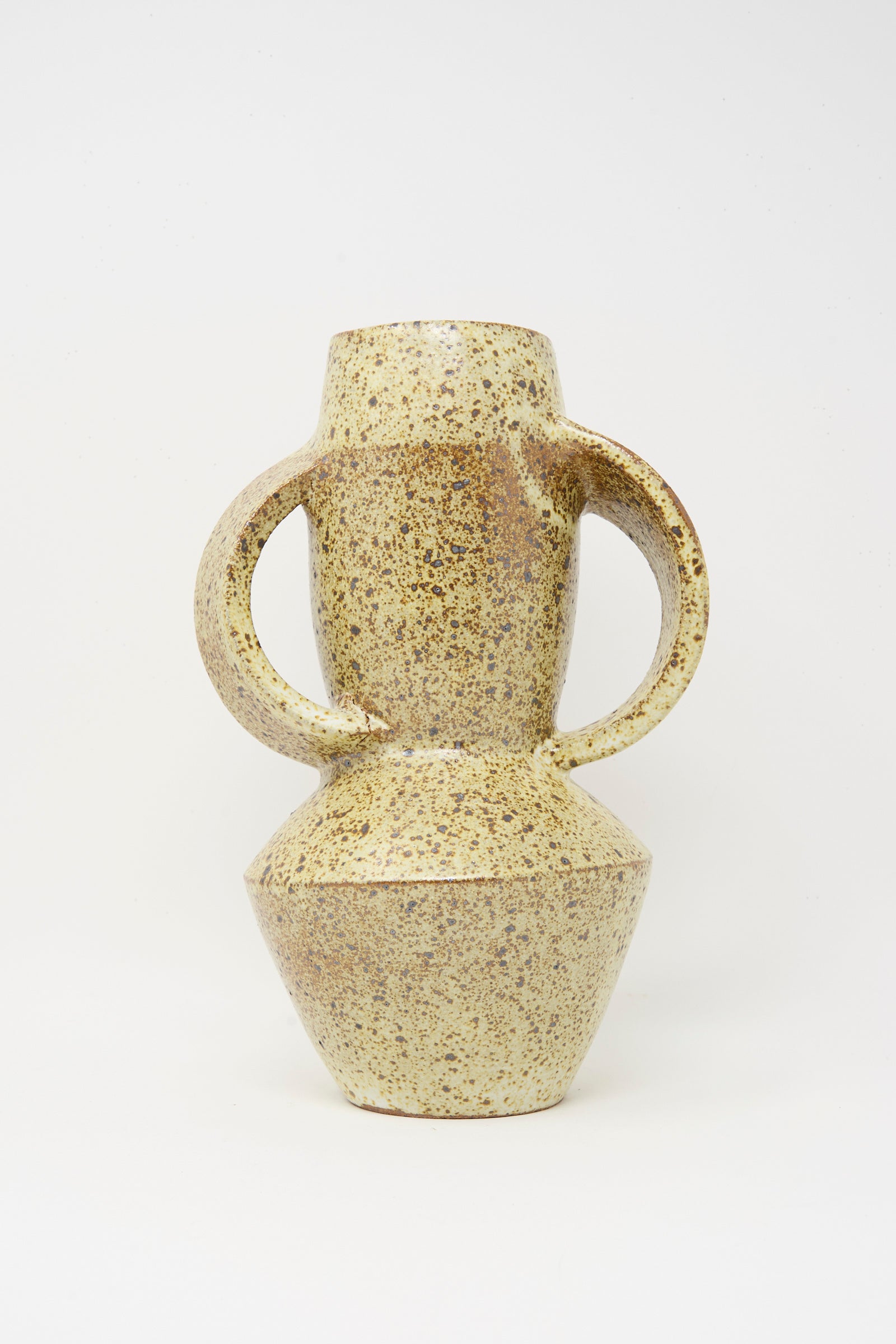 The Tall Shaped Handled Vase in Eggshell Speckle by Rachel Craven features two large circular handles, a narrow neck, and a geometric base. Wheel-thrown in Los Angeles, it’s shown against a plain white background.
