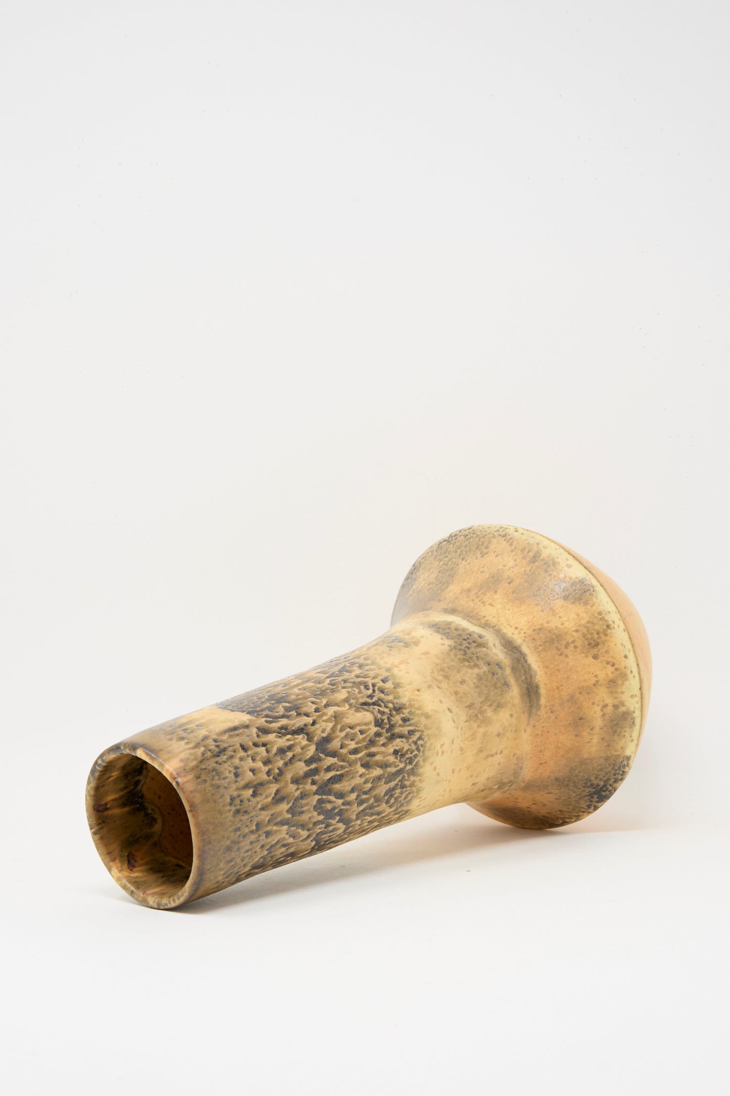 The Rachel Craven Tall Variegated Vase in Black and Brown features a textured, cylindrical, wheel-thrown clay design with a flared base, shown lying on its side against a plain white background.