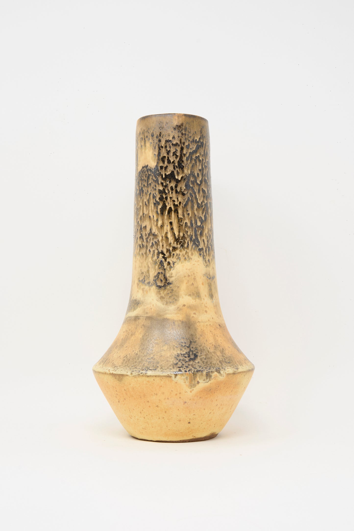 The Tall Variegated Vase in Black and Brown by Rachel Craven is a handmade piece with a narrow neck, wide base, and yellowish-brown mineral glaze highlighting dark textured patterns on the upper half.