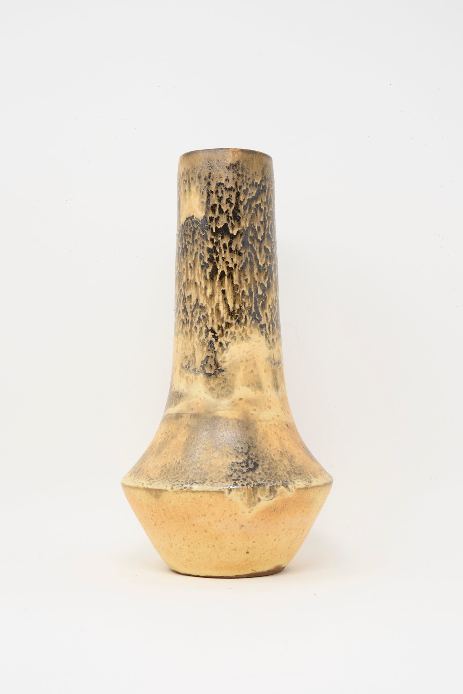 The Tall Variegated Vase in Black and Brown by Rachel Craven is a handmade piece with a narrow neck, wide base, and yellowish-brown mineral glaze highlighting dark textured patterns on the upper half.