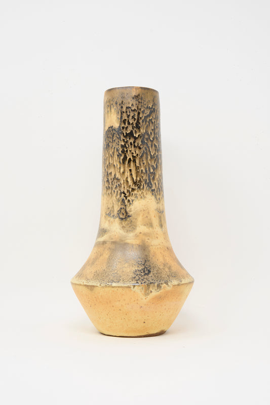 The Tall Variegated Vase in Black and Brown by Rachel Craven is a handmade piece with a narrow neck, wide base, and yellowish-brown mineral glaze highlighting dark textured patterns on the upper half.
