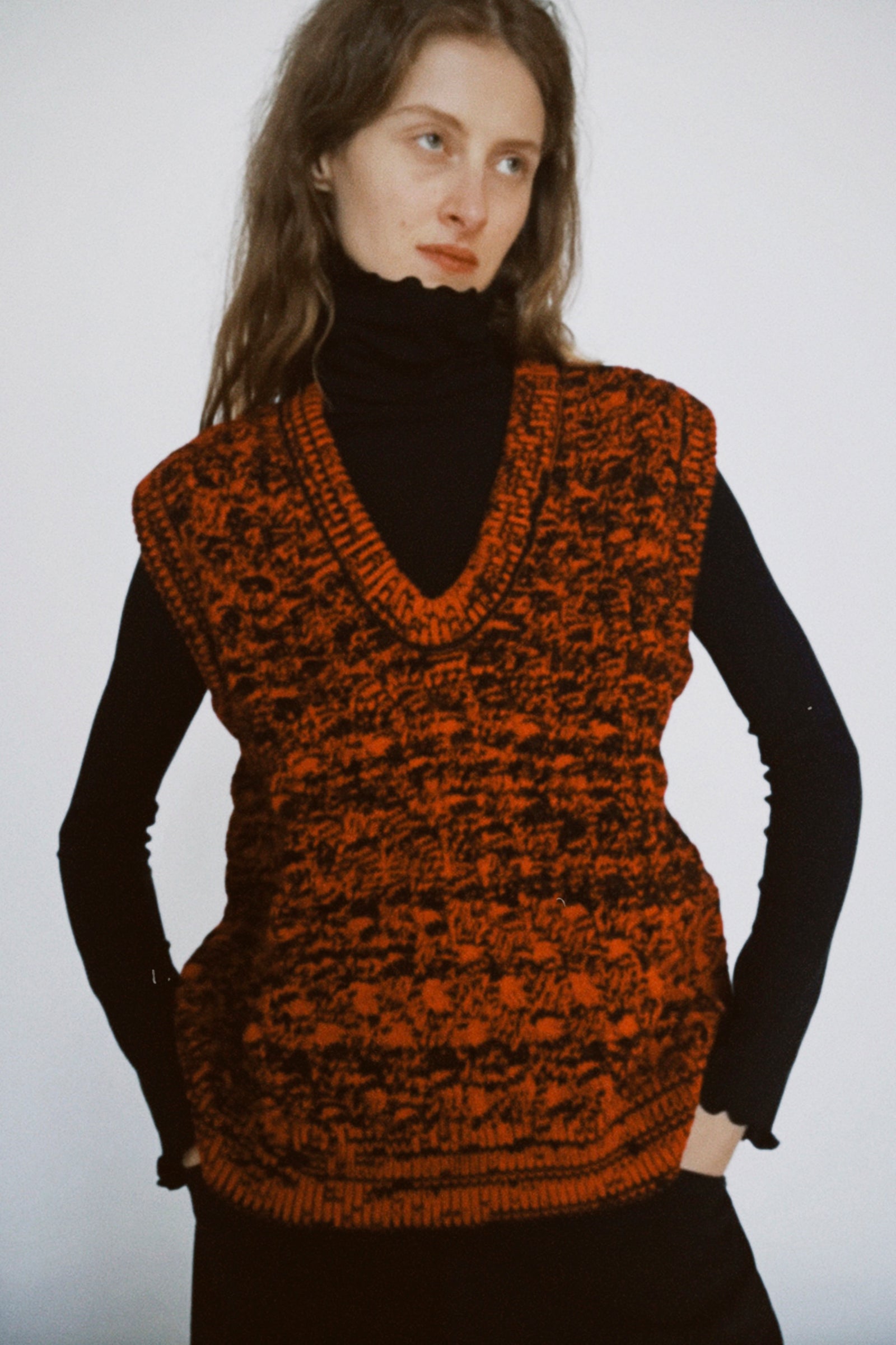 A polaroid of a woman wearing Rachel Comey's Mati Vest in Red Marble with a black turtleneck underneath, against a white background.