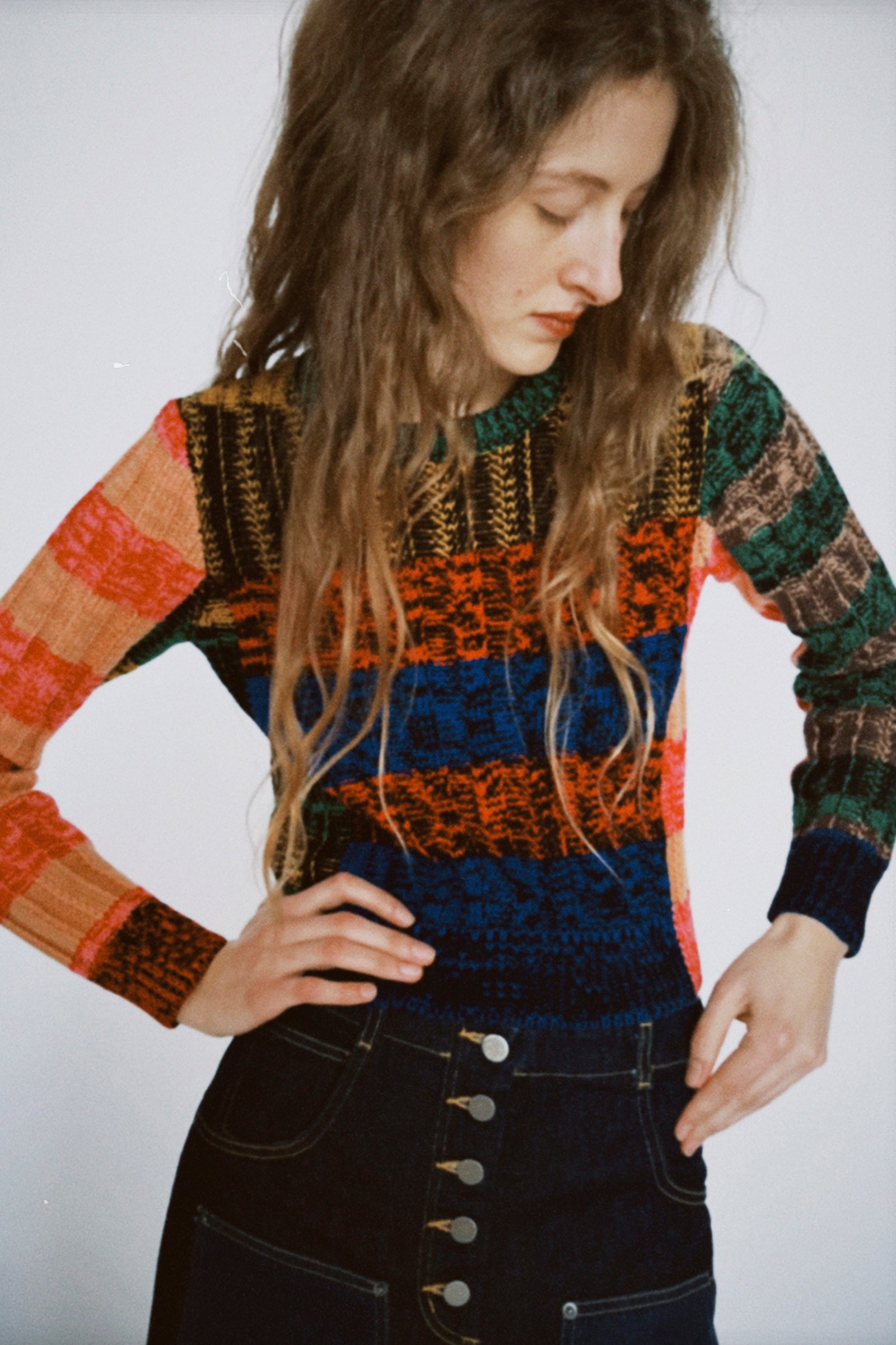 A polaroid of a woman wearing Rachel Comey's Muna Pullover in Stripe Multi, and the Handy Pant in Dark Indigo against a white wall.