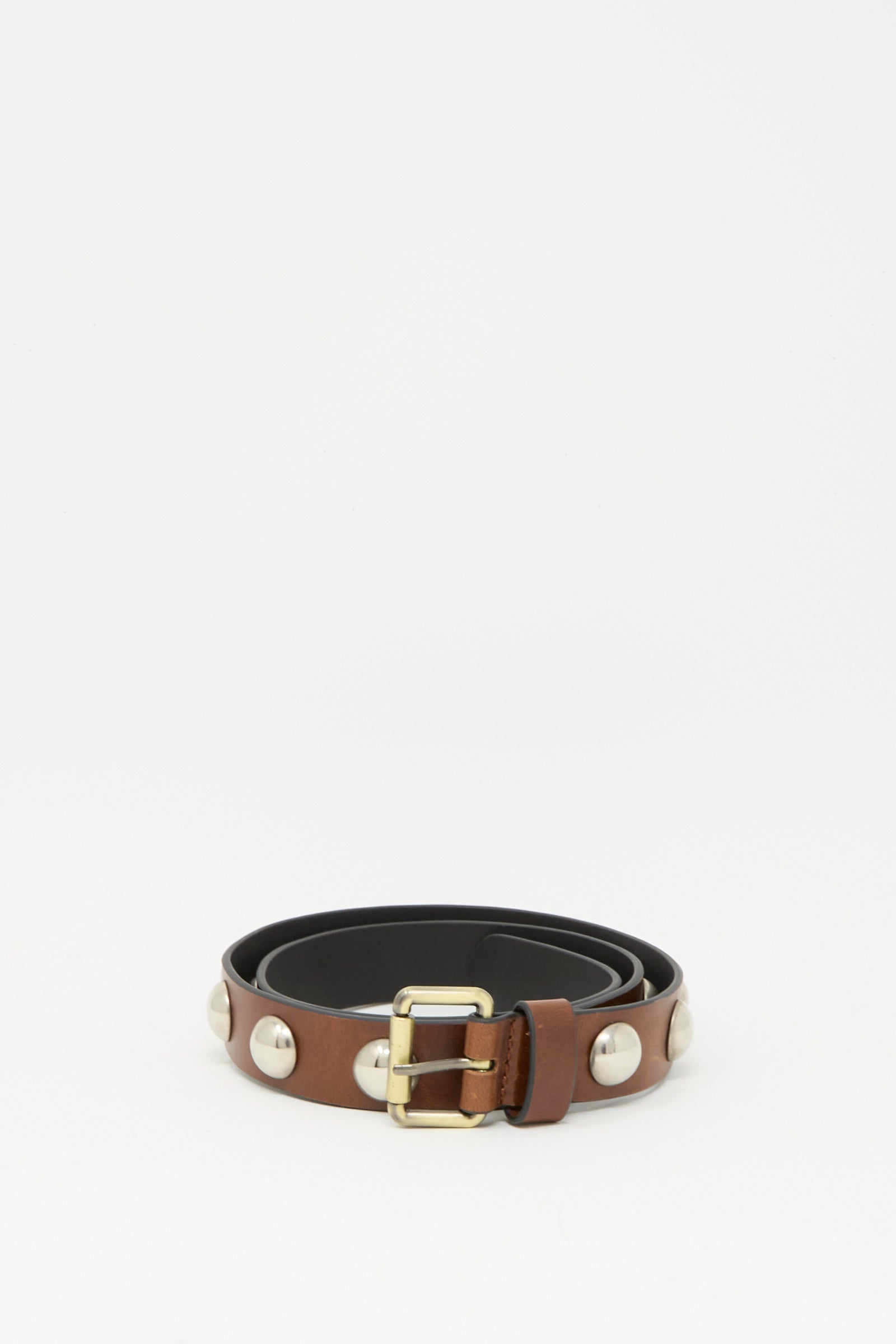The Rachel Comey Studded Belt in Saddle, featuring a dark brown leather strap with large silver studs and a bronze buckle, is coiled neatly on a plain white background.
