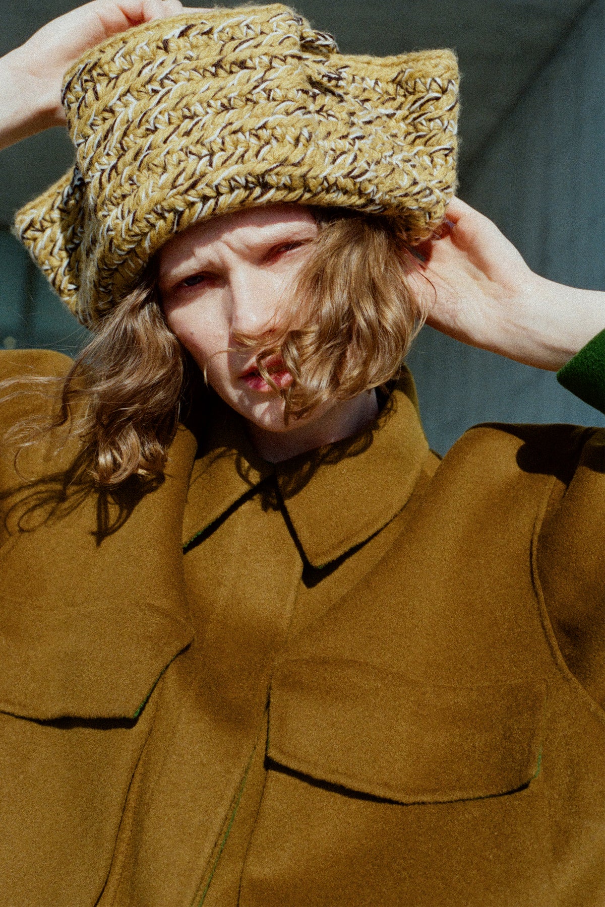 A close up of a woman wearing Rachel Comey's Tricorn in Dark Gold Marle, and Site Jacket in Bronze.