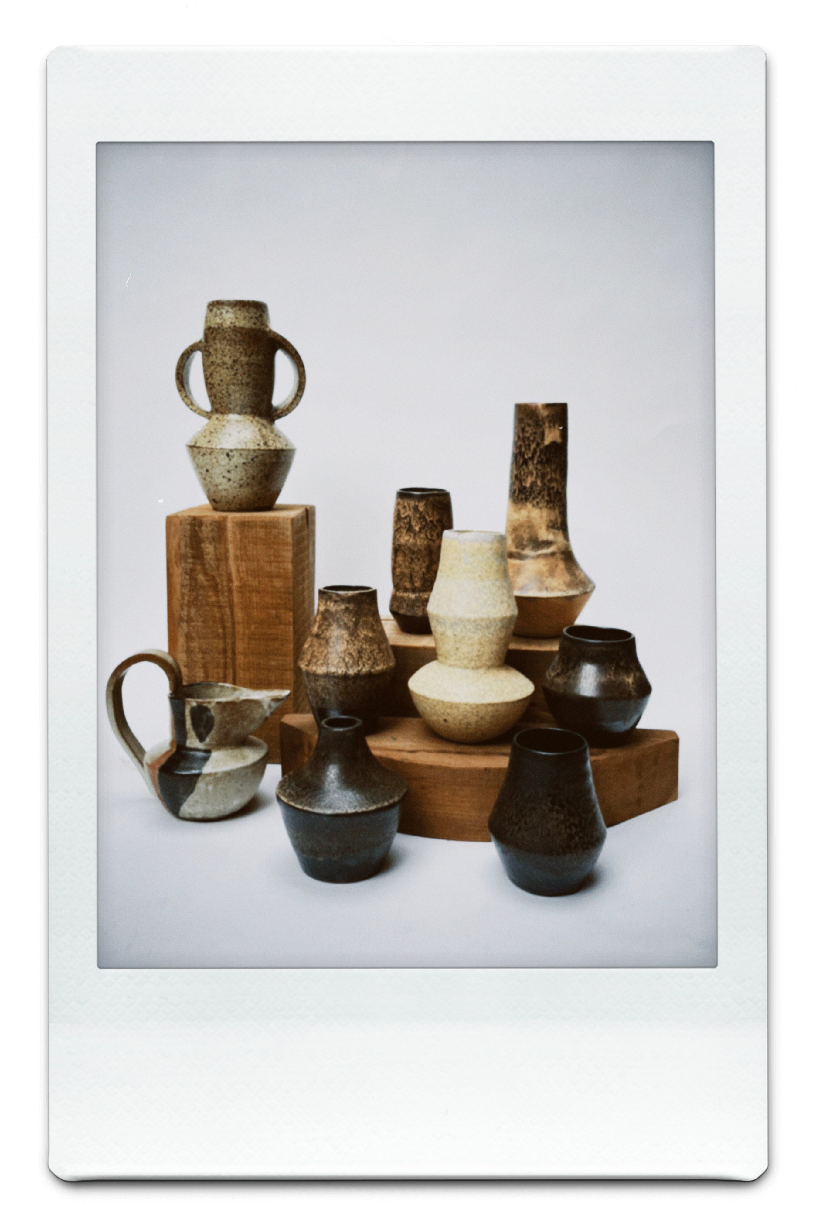 Collection of ceramic vases and bowls on a wooden stand with a white border