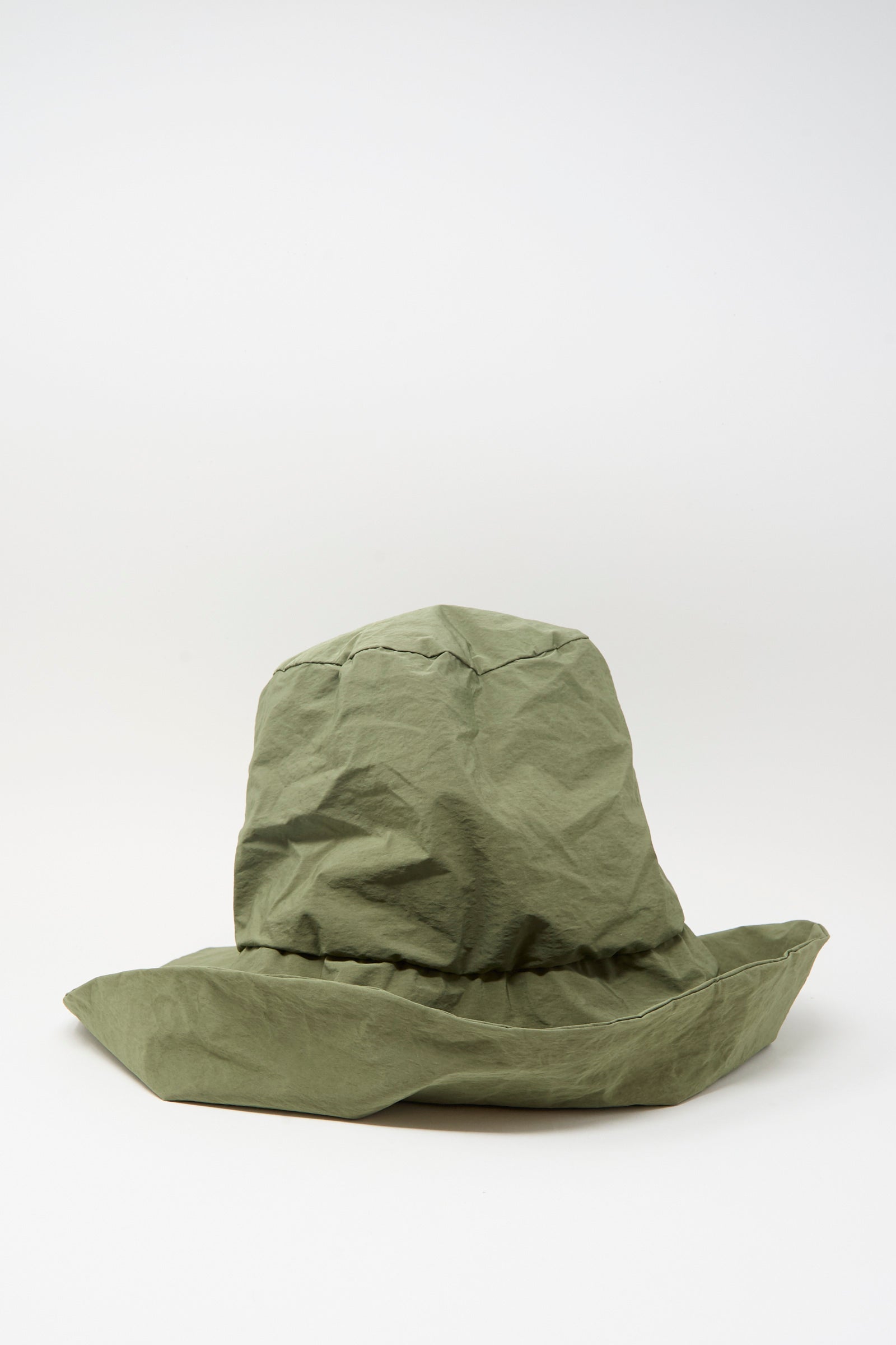 The Bianca Hat in Green by Reinhard Plank, a crumpled olive-green cotton bucket hat with a wide brim, is displayed against a plain white background.