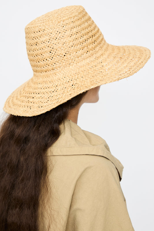 A person with long brown hair wears the Mais Lai Hat in Natural by Reinhard Plank and a beige jacket, shown from behind against a plain background, evoking the timeless charm of Florence, Italy.