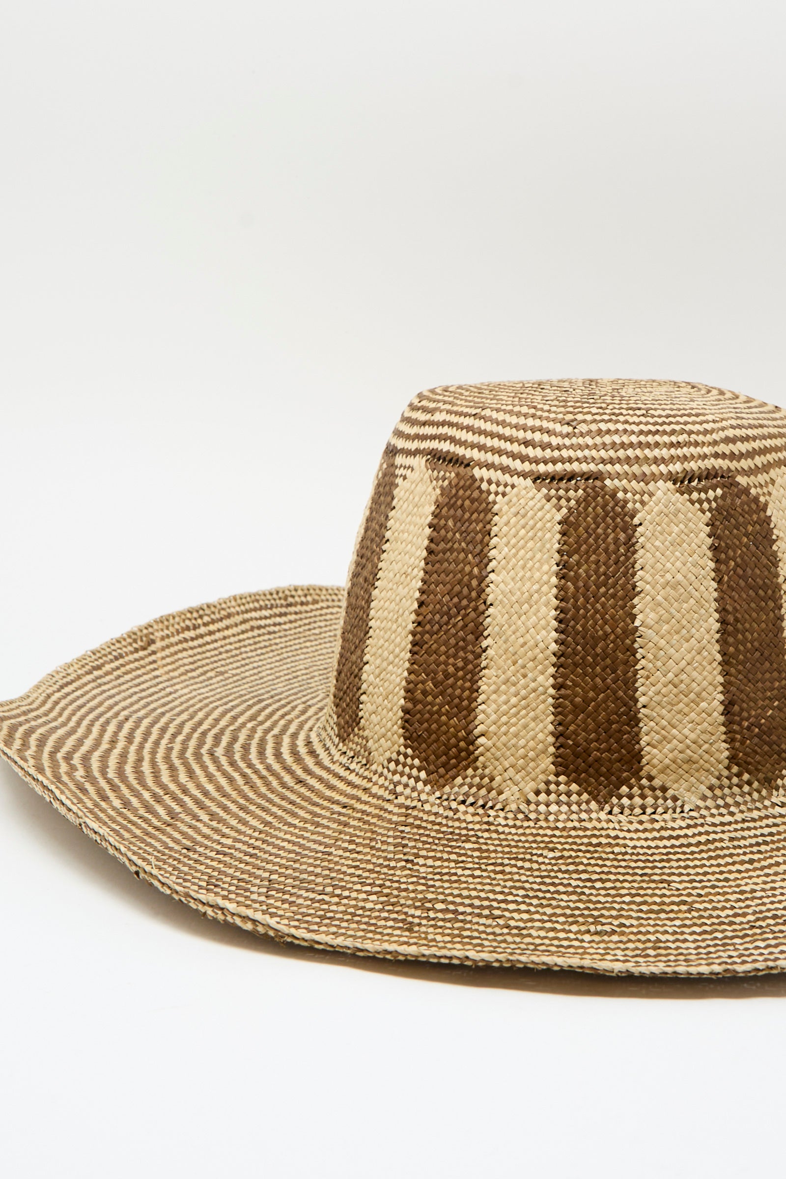 The Reinhard Plank Straw Beghe Lai Hat in Natural Stripes, made in Italy, features a wide brim and alternating dark and light vertical stripes on the crown, shown against a plain white background.
