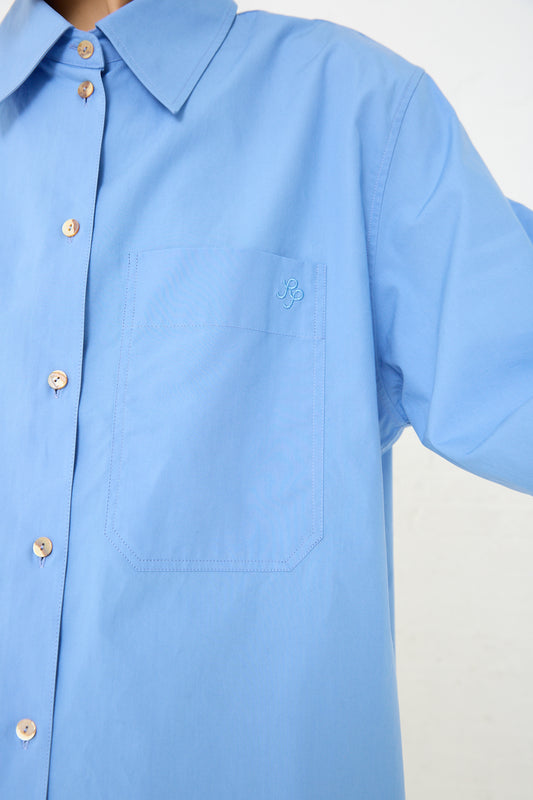 A woman wearing a Rejina Pyo Caprice Shirt in Blue, made from organic cotton and featuring a pocket.