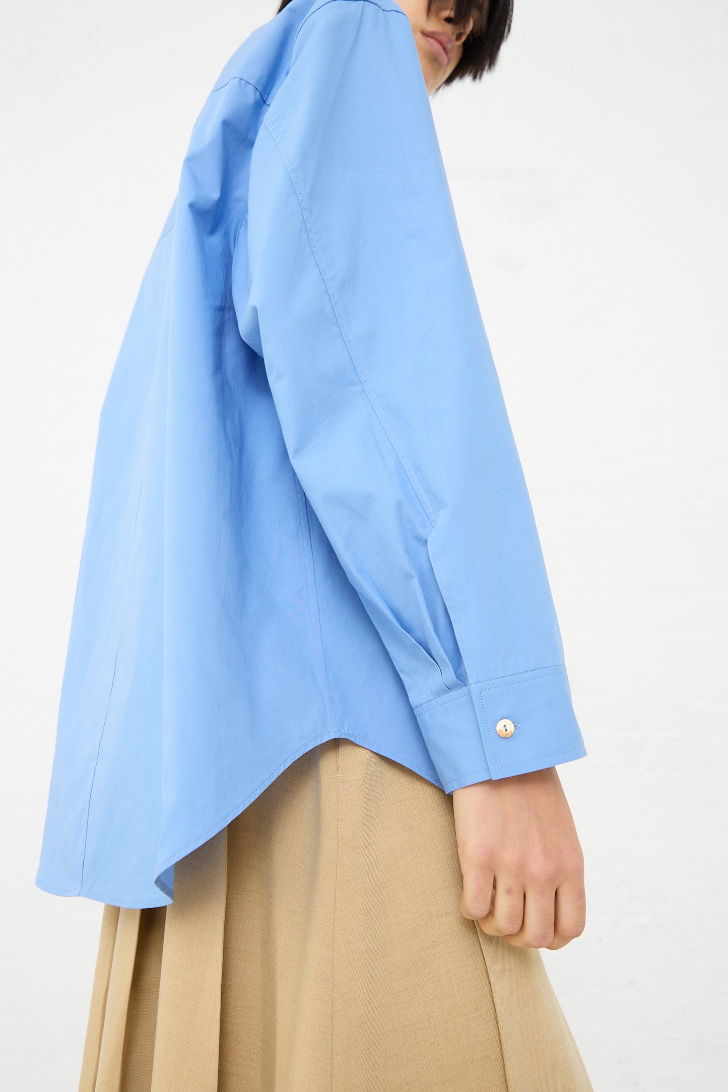 The model is wearing an oversized, long sleeve Caprice Shirt in Blue made of organic cotton by Rejina Pyo. Side view.