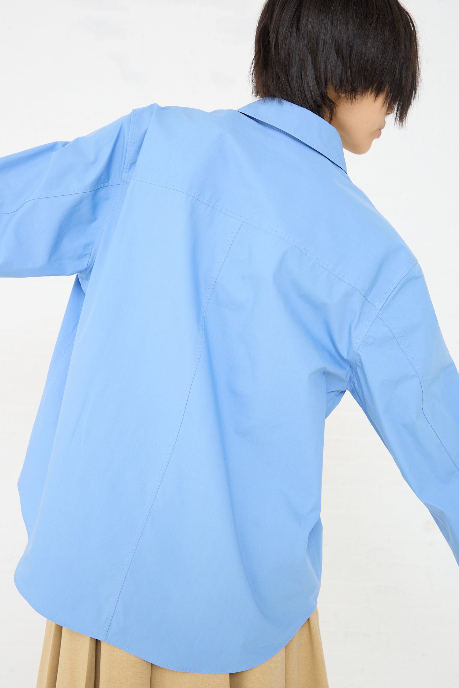 A woman wearing a Rejina Pyo Caprice Shirt in Blue. Back view.