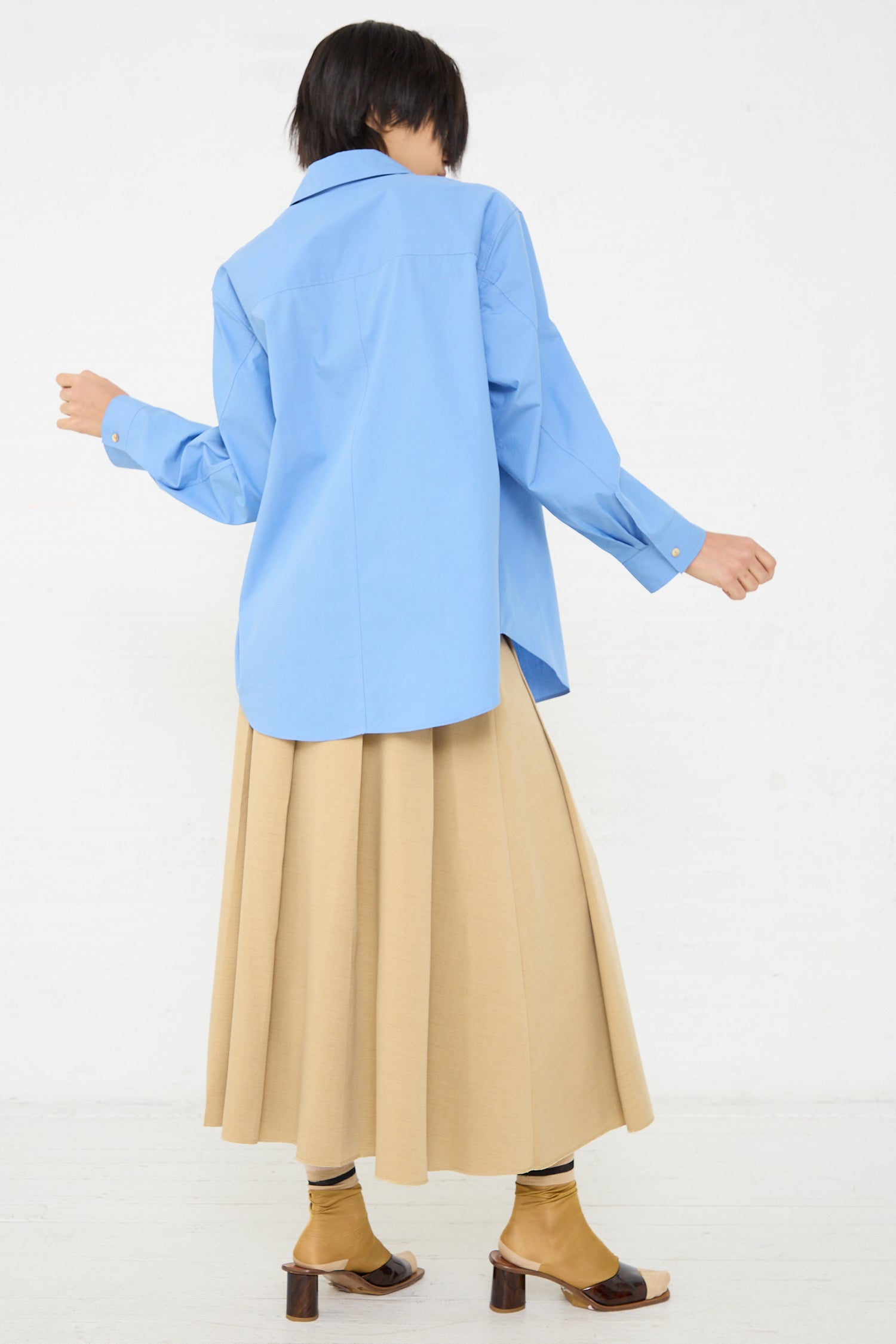 The back of a woman wearing an oversized fit, long sleeve Caprice shirt in blue by Rejina Pyo.