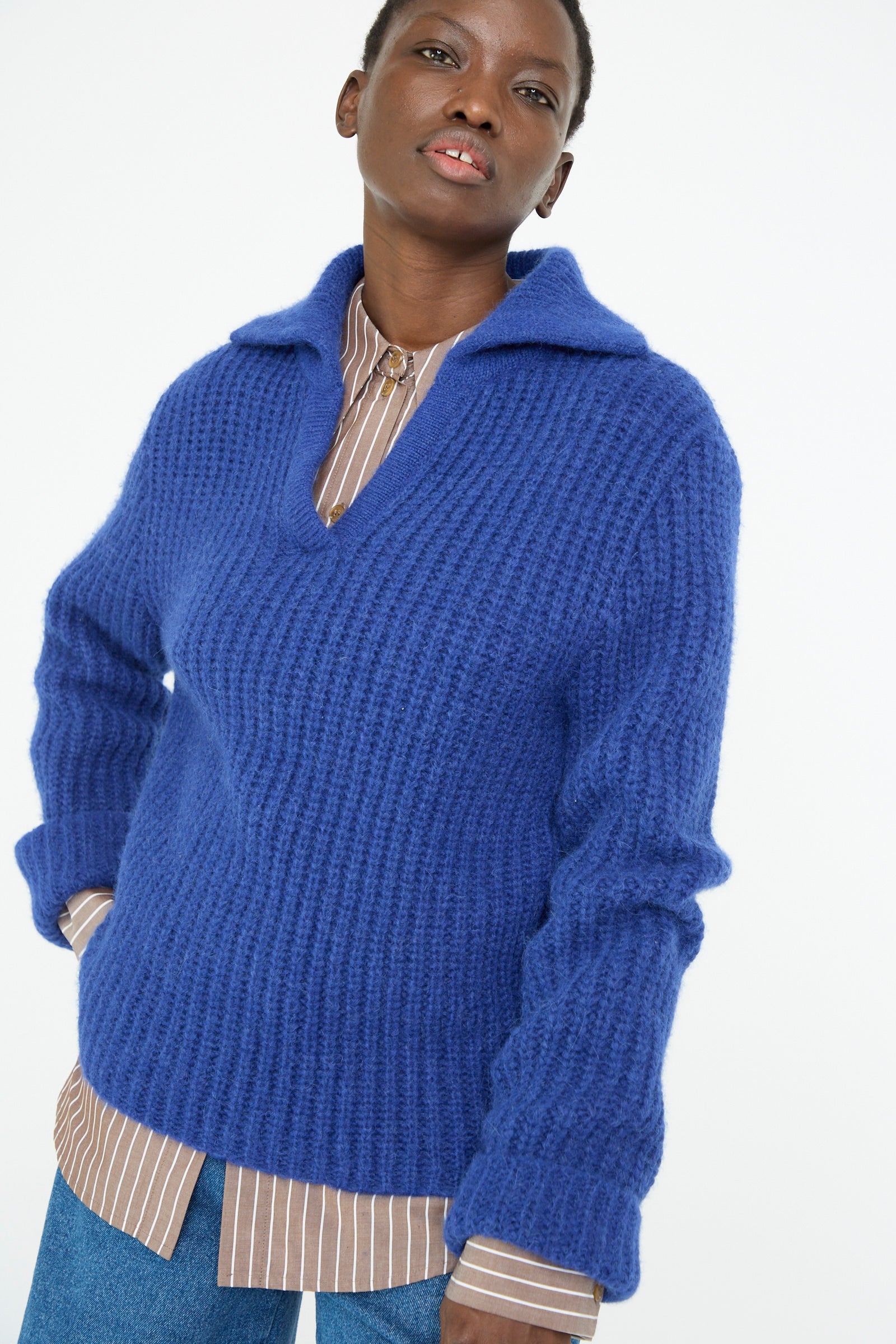 A person is wearing the Rejina Pyo Chunky Alpaca Alison Sweater in electric blue over a brown striped shirt against a plain background.