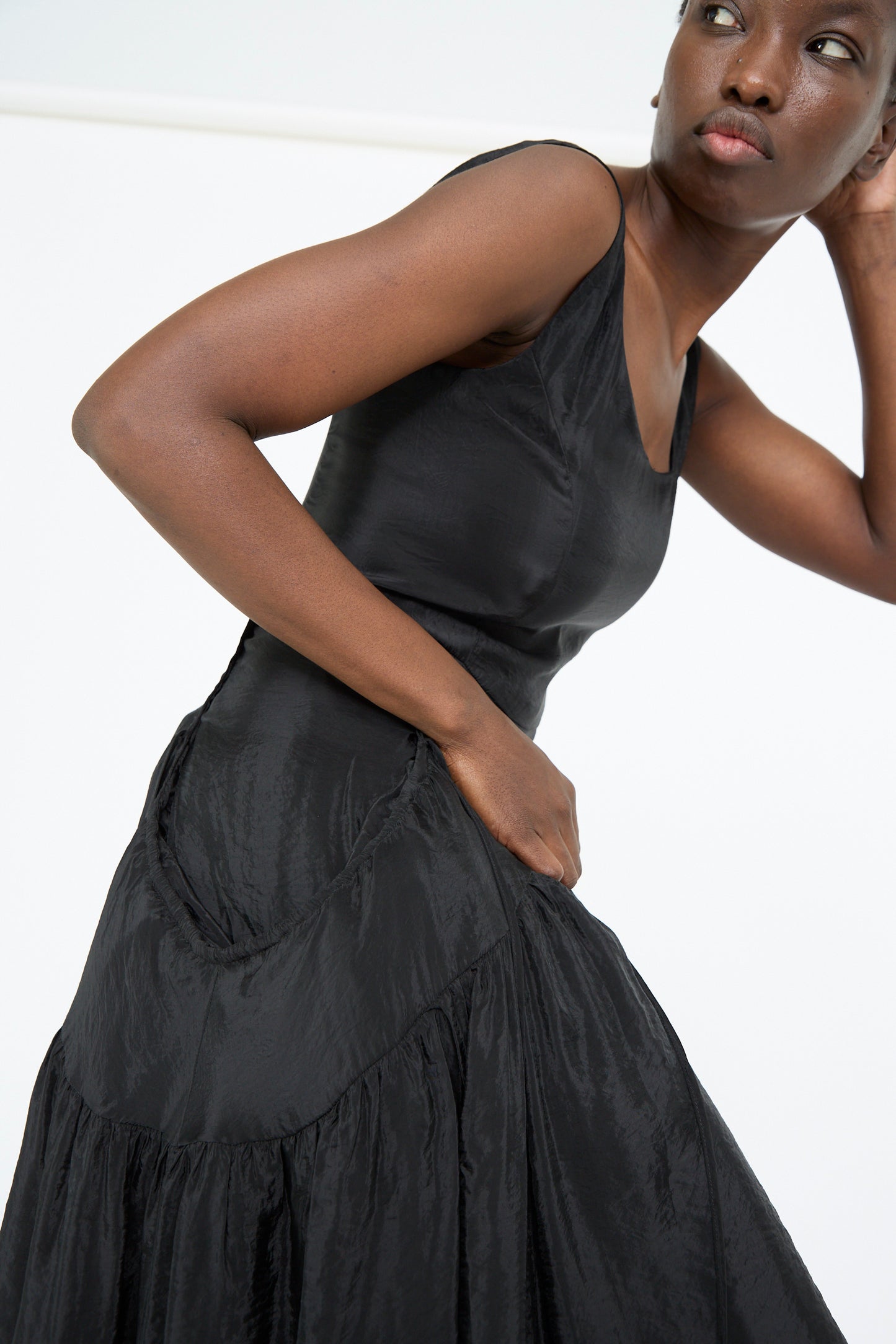 Wearing the Erica Dress in Black by Rejina Pyo, the person looks gracefully to the side.