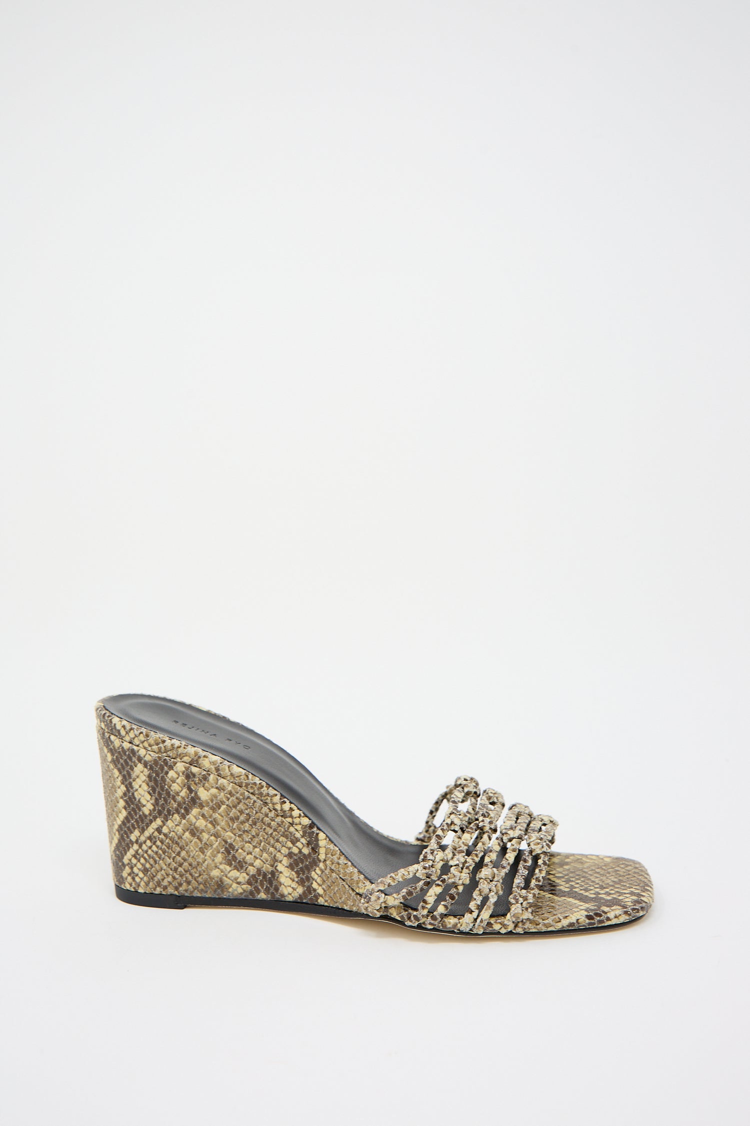 A single Rejina Pyo Leather Print Kyle wedge sandal in Snake Butter with embellishments and a woven front strap on a white background.