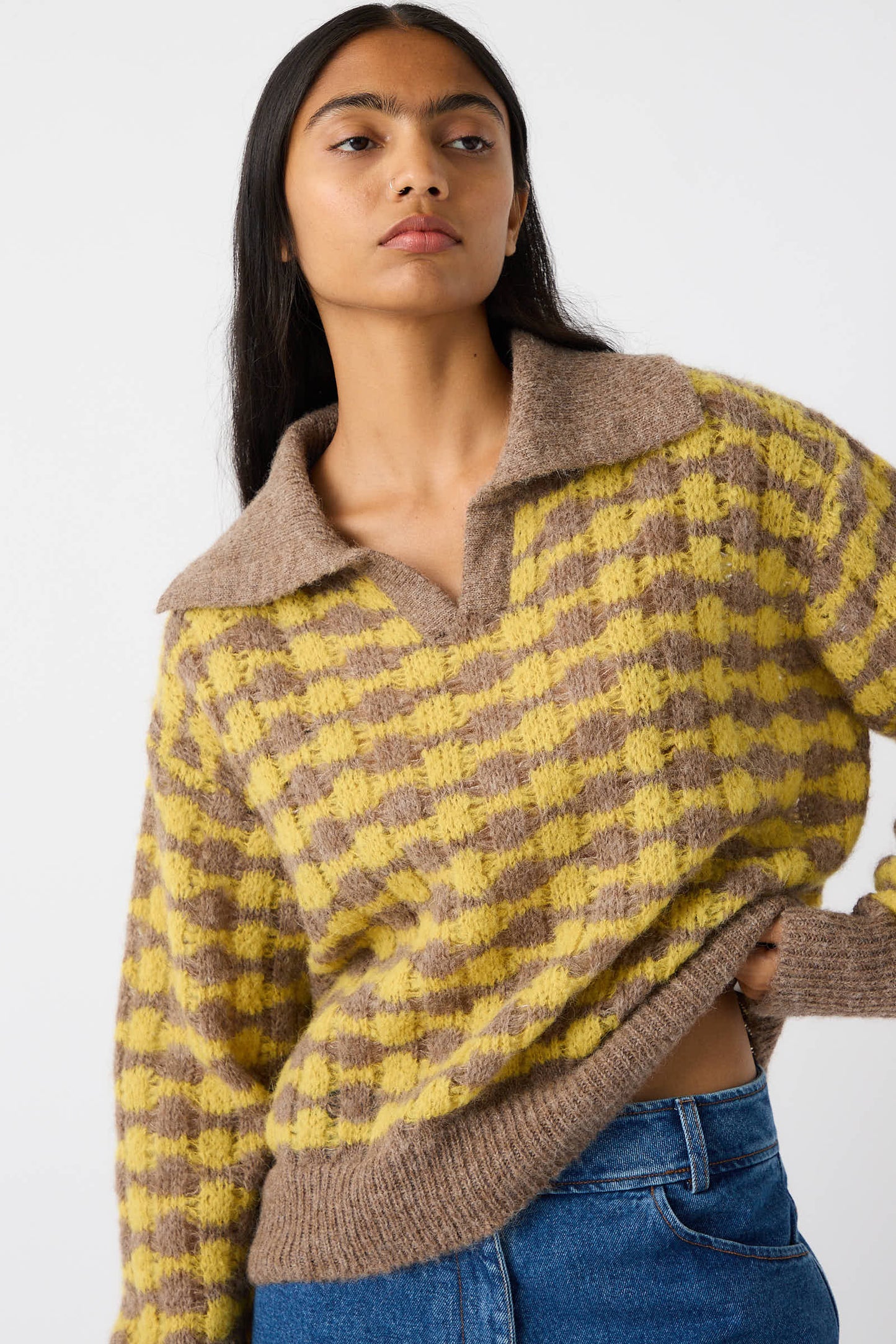 A person with long, dark hair wears the Rae Sweater in Yellow by Rejina Pyo, paired with blue jeans, standing against a plain white background.