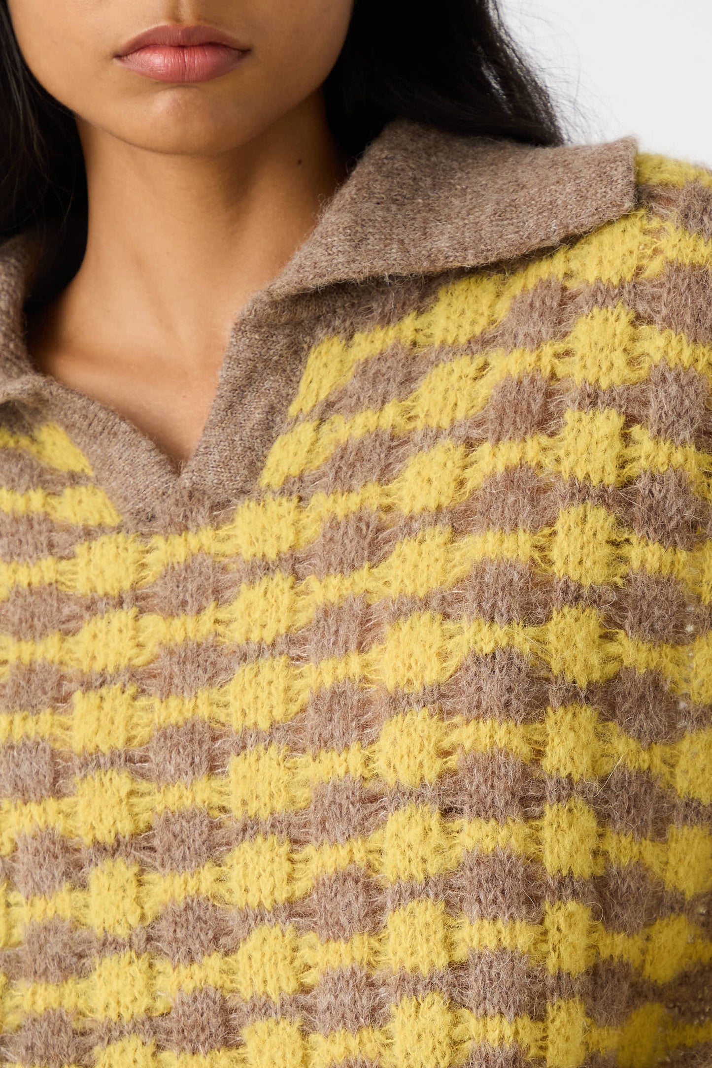 Close-up of a person wearing the Rae Sweater in Yellow by Rejina Pyo, featuring a relaxed fit, knitted design with a yellow and brown checkered pattern and a collar.