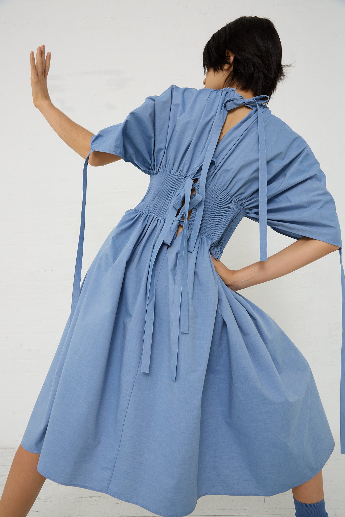A woman in a Renata Brenha Cotton Sanfona Dress in Denim Blue is posing.