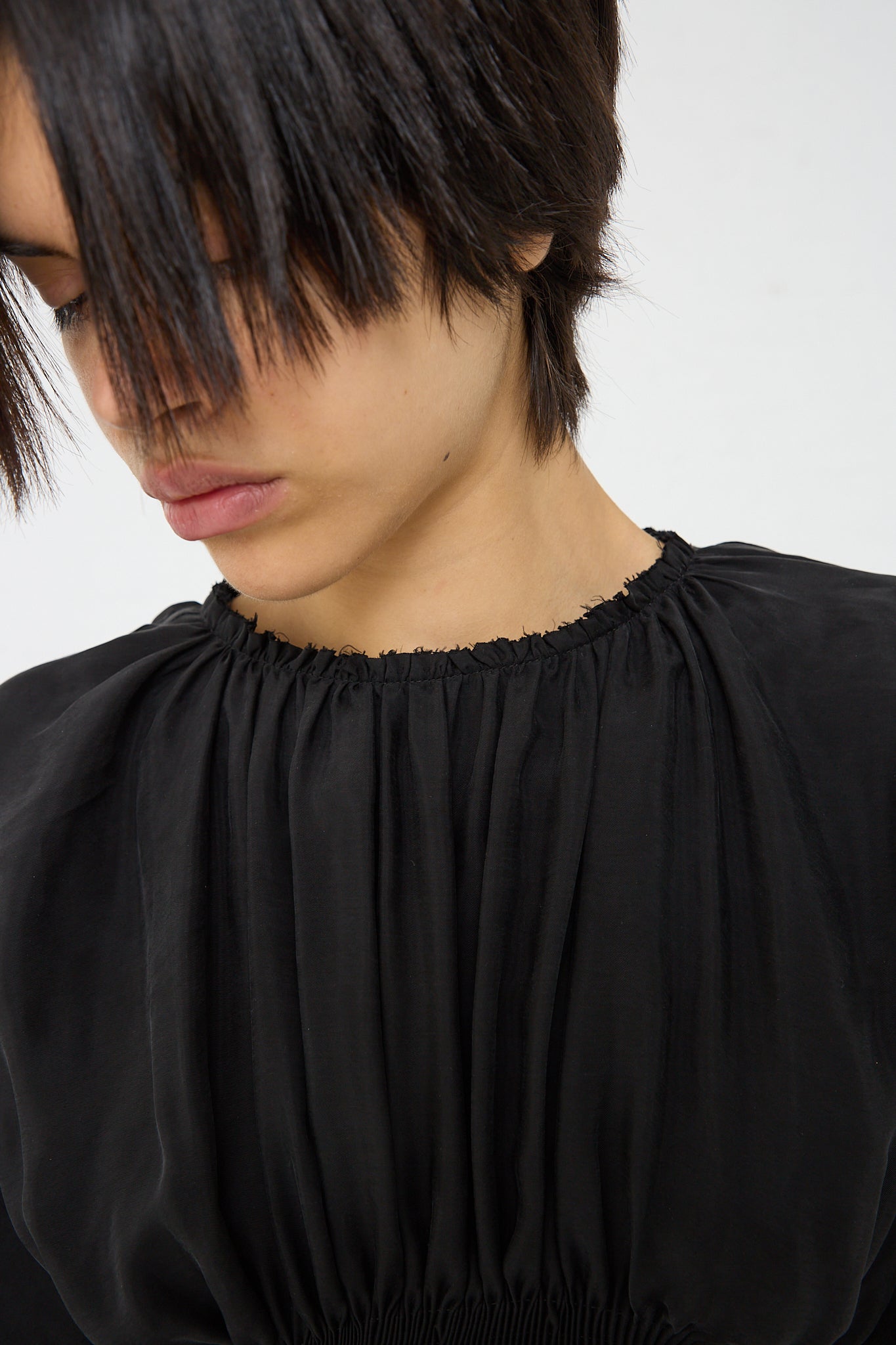 A woman wearing a Renata Brenha Cupro Sanfona Top in Washed Black with ruffles made from recycled cupro. Up close, front view.