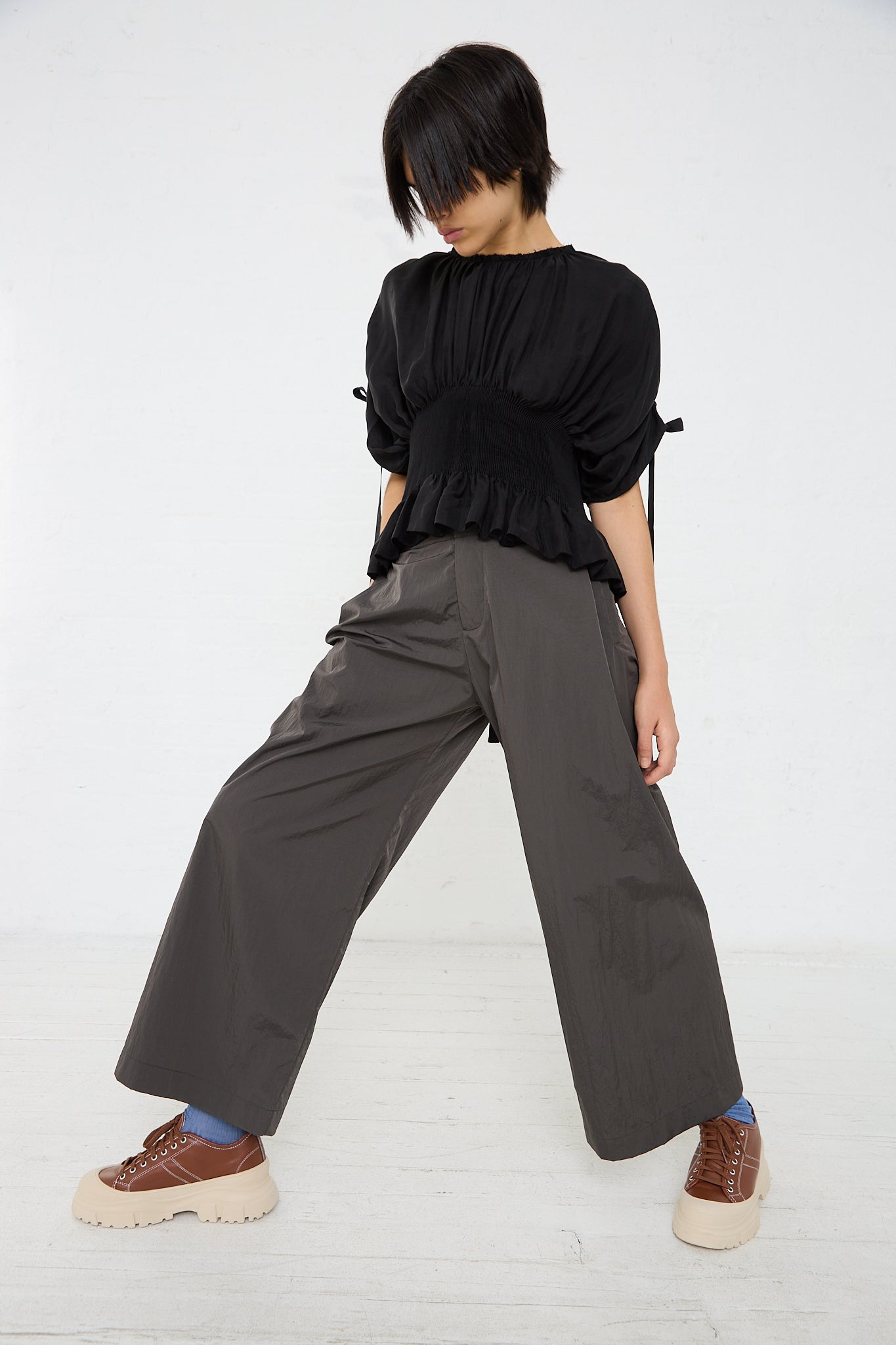 A woman wearing a black top and Renata Brenha's Mare Trouser in Deep Grey wide leg pants.