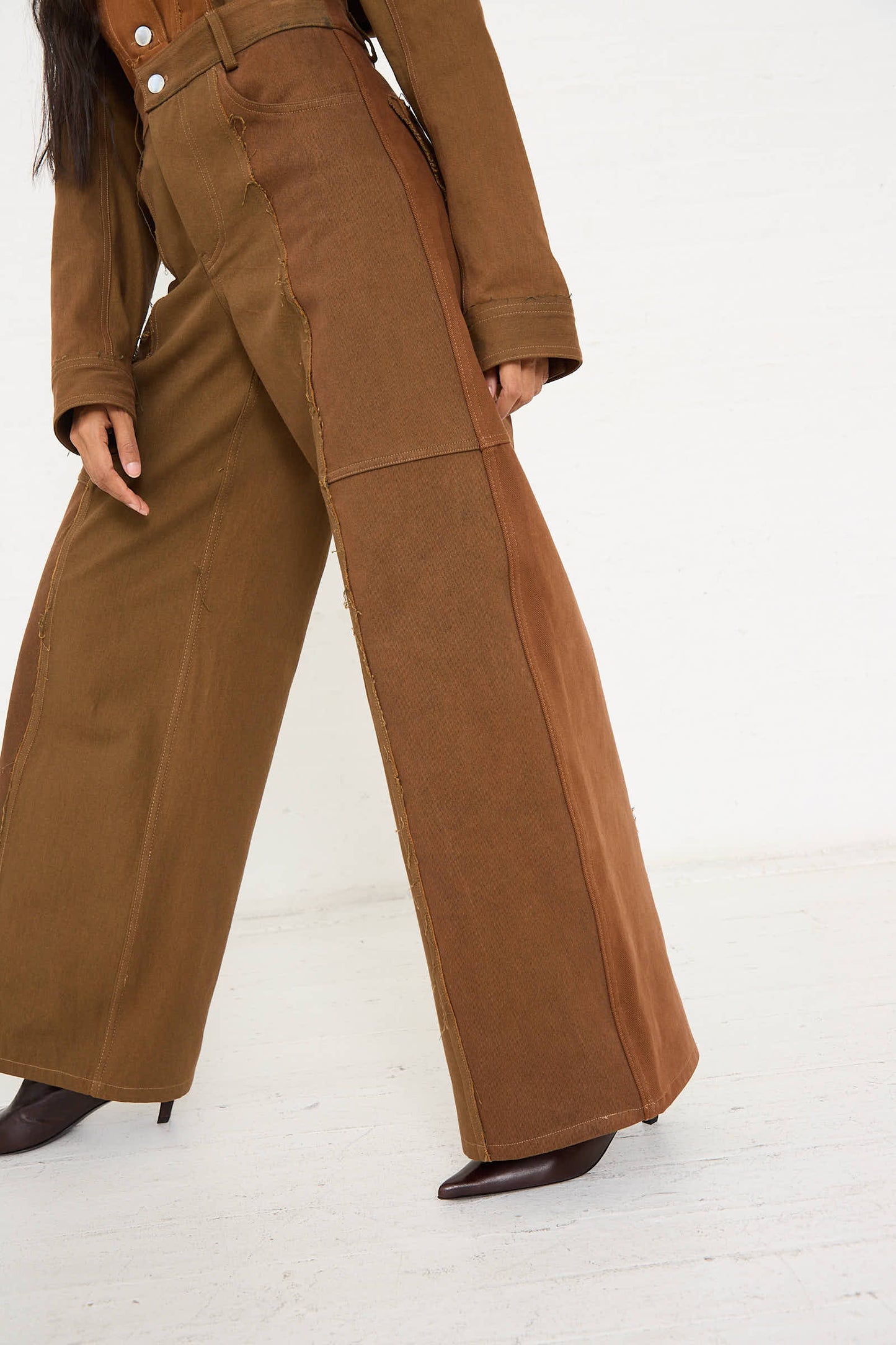 Person wearing Renata Brenha's Upcycled Denim Cangaço Trouser in Brown with front seam details and brown heeled shoes, against a plain light background. The person's upper body is partially visible, showcasing a relaxed fit perfect for any casual outing.