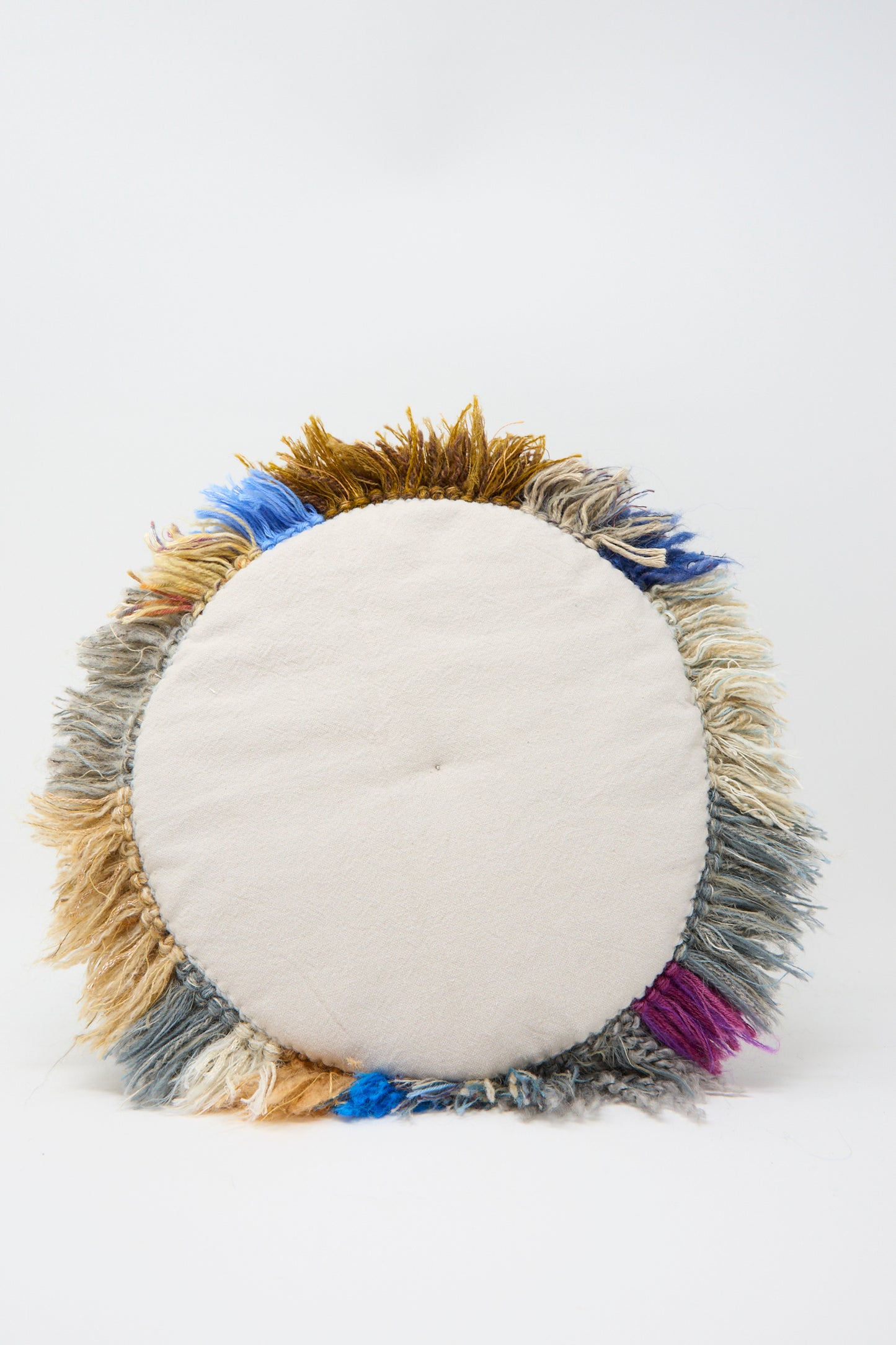 The Handmade Cushion in Multi XIV by Renilde De Peuter features a circular design with a plain center and multicolored fringes in brown, blue, purple, and beige. Crafted from recycled yarns using the Smyrna stitch technique, this cushion stands out on a white background.